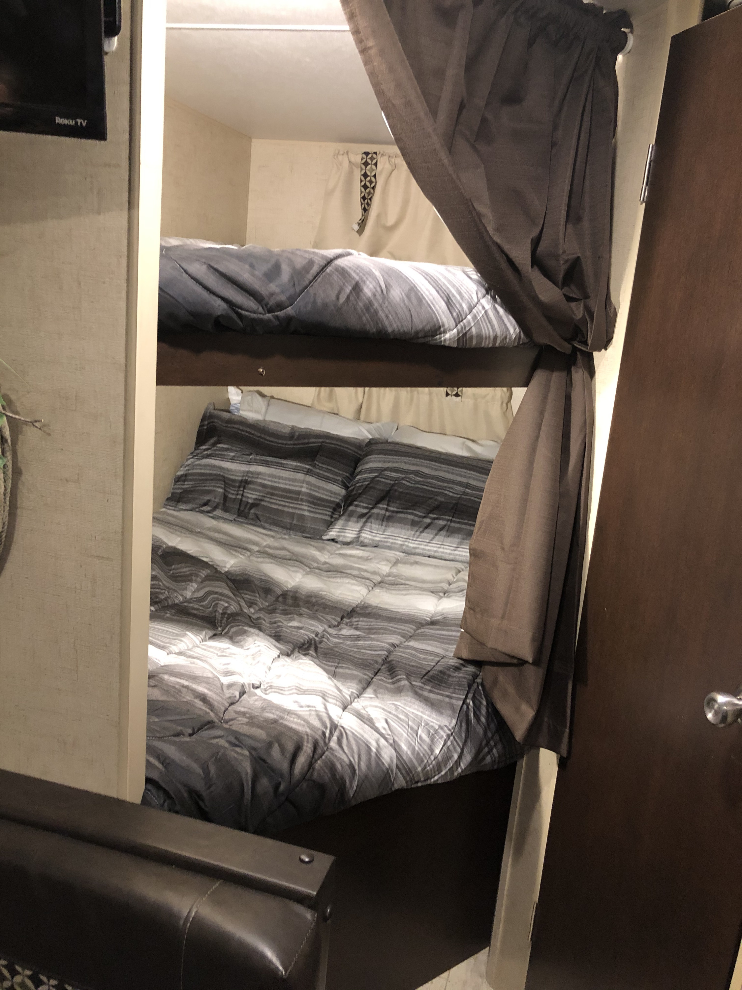 Cozy RV rental bunk beds with striped bedding and privacy curtains, ideal for family sleeping in a compact space.. Other Other 2017
