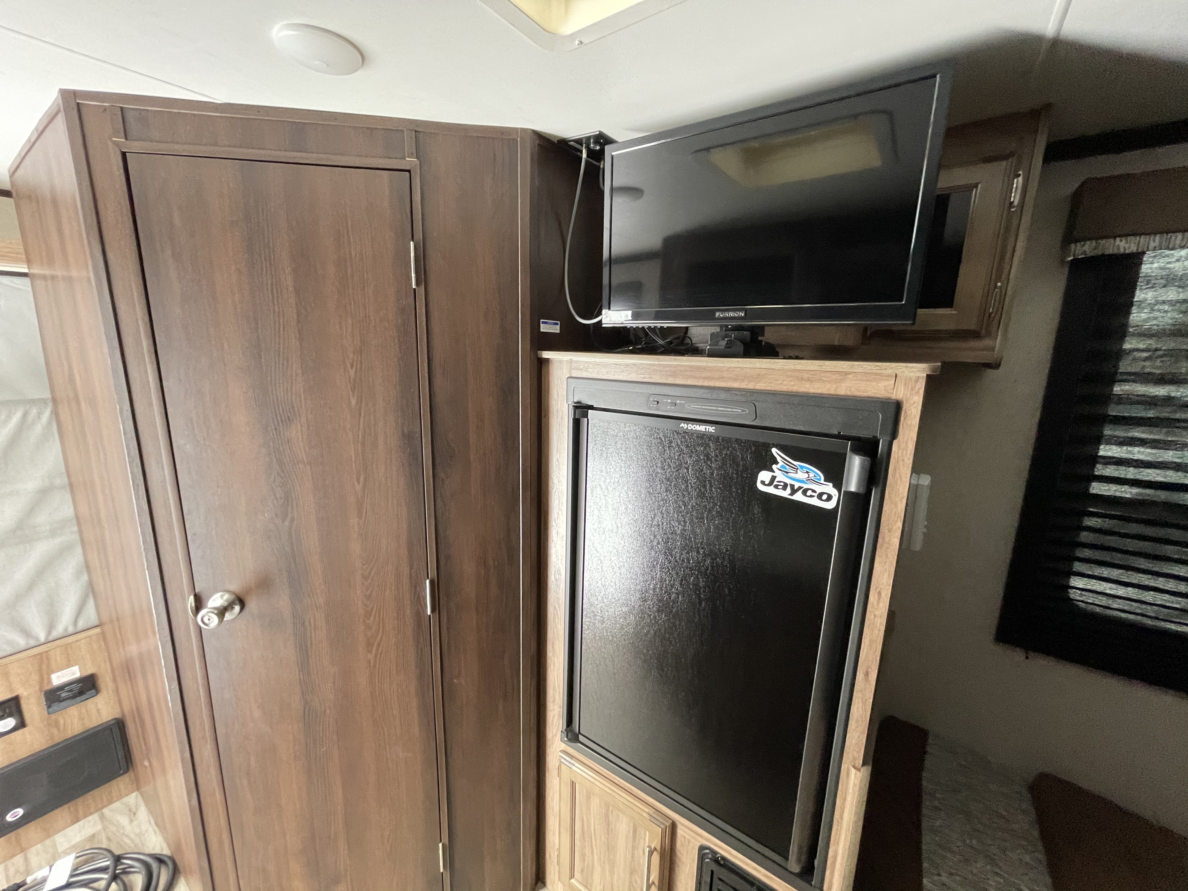 Cozy RV rental interior with a Furrion TV, Dometic fridge, and wood cabinetry for your journey.. Jayco Jay Feather Baja 2018