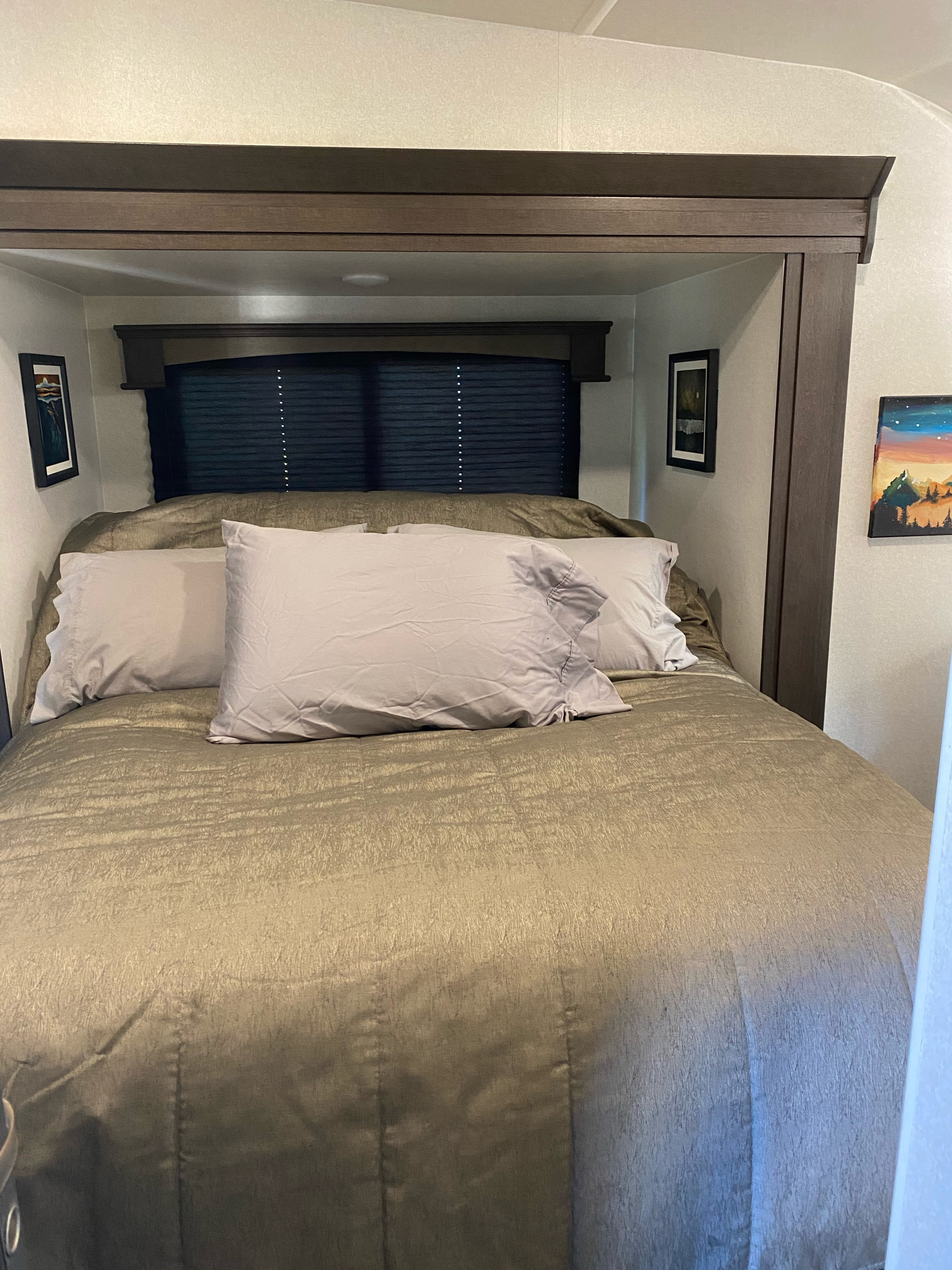 A comfortable, inviting bedroom in an RV rental, featuring a large bed with grey pillows and a gold comforter.. Forest River Shockwave 2020