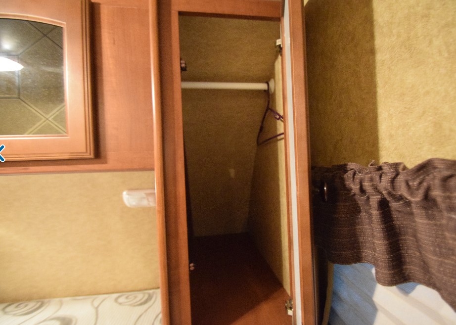 RV rental: Interior view of an open wardrobe with a hanging rod, adjacent mirrored cabinet, and window curtain.. Heartland North Trail 2012