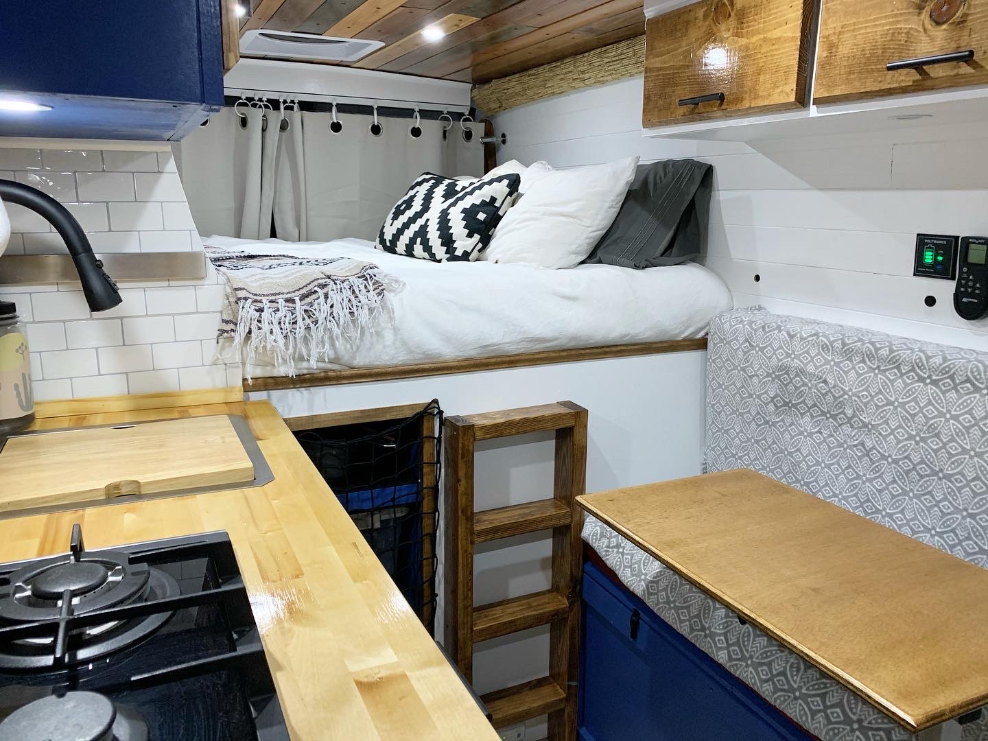This cozy RV rental interior features a compact kitchen, elevated bed with a ladder, and a convertible dining area.. Dodge RAM Promaster 2500 159' Wheelbase 2017