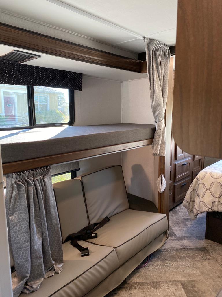 Cozy RV rental interior with bunk beds, a sofa with seatbelts, and a glimpse into the rear bedroom area.. Forest River Forester 3251DS 2021