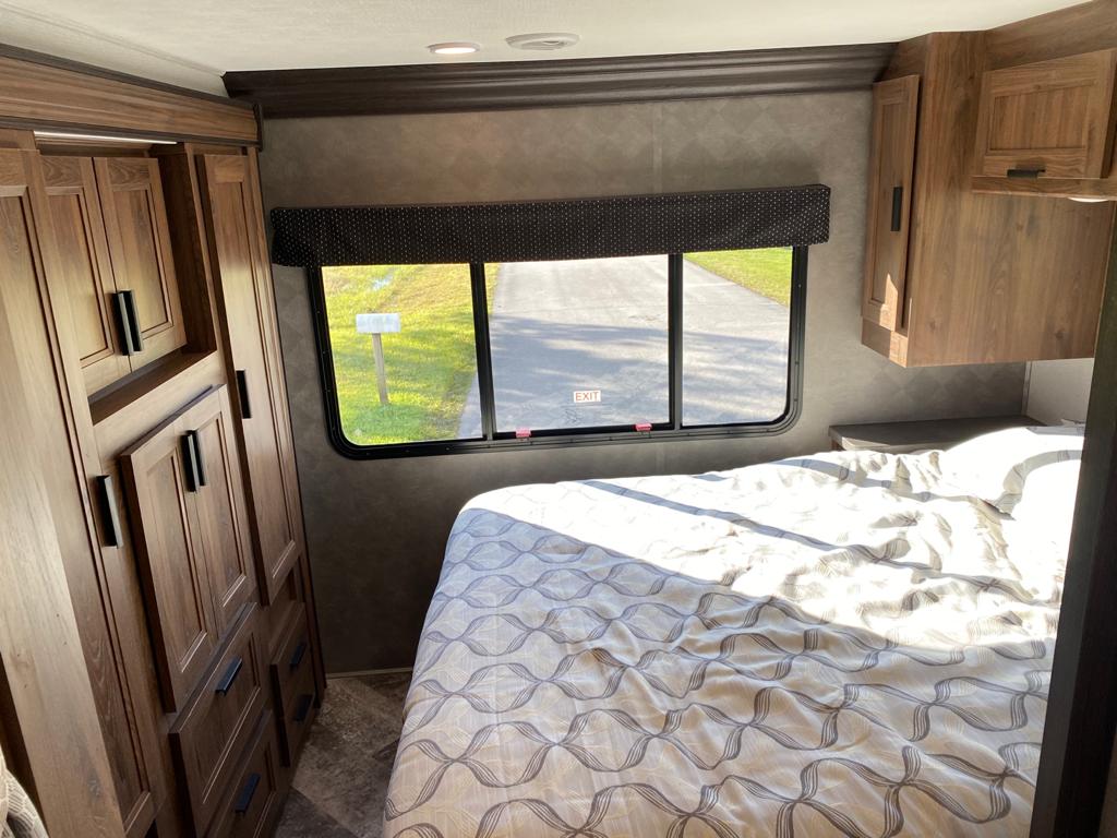 Cozy RV rental bedroom featuring a comfortable bed, built-in storage cabinets, and a window view of the outdoors.. Forest River Forester 3251DS 2021
