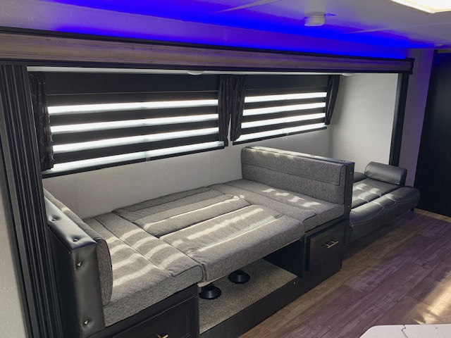 Spacious rv rental interior features versatile gray convertible seating and lounge, with under-seat storage and blue LED lights.. Cherokee Grey Wolf 27DBH 2021