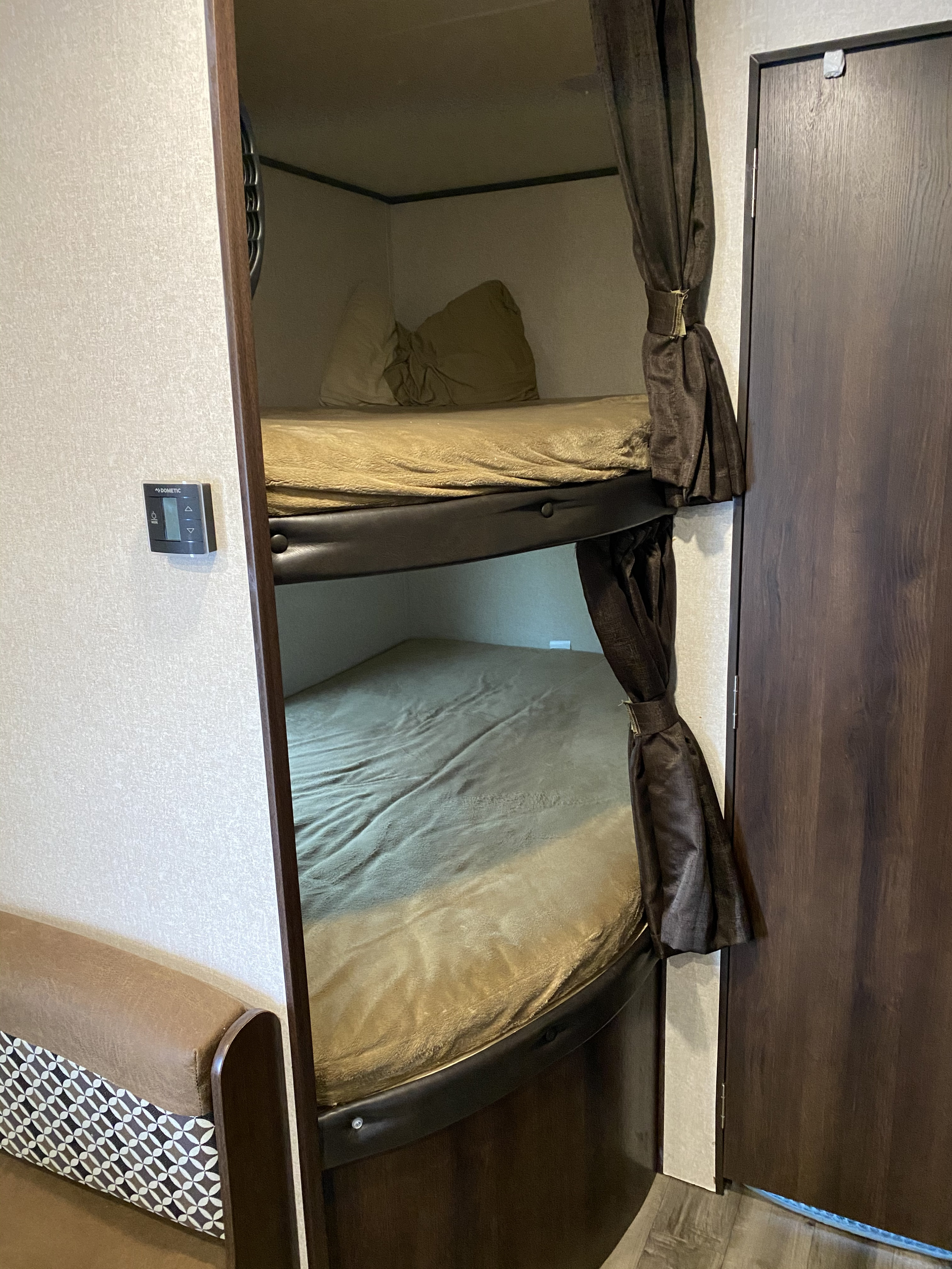 Cozy RV rental interior featuring twin bunk beds with soft blankets, a Dometic thermostat, and dark privacy curtains.. Jayco Jay Flight 2018