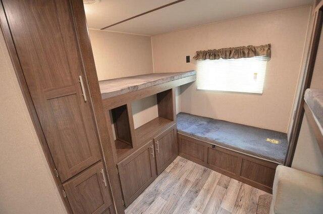 RV rental interior with bunk beds, storage cabinets, and a window, creating a functional and compact sleeping area.. Keystone Hideout 2020