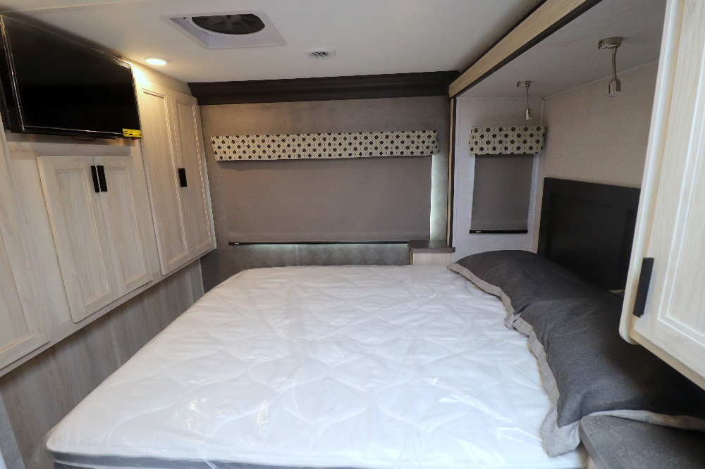 RV rental bedroom: a clean, modern space with a new mattress, mounted TV, light wood cabinets, and window shades.. Forest River Forester 2022