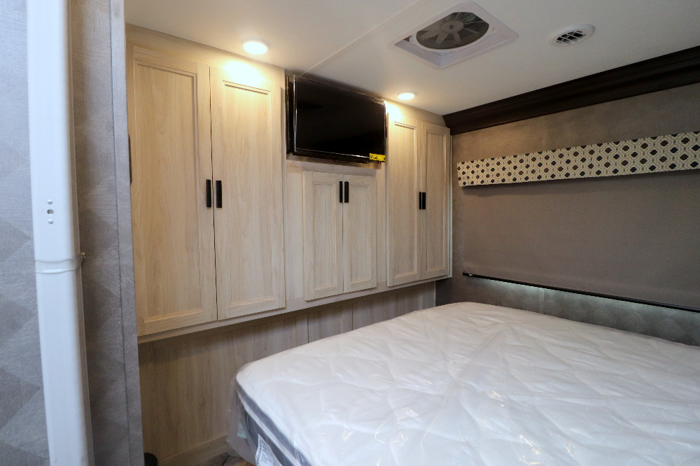 New mattress and ample storage in this cozy RV rental bedroom. Features include overhead cabinets, TV, and ceiling fan.. Forest River Forester 2022