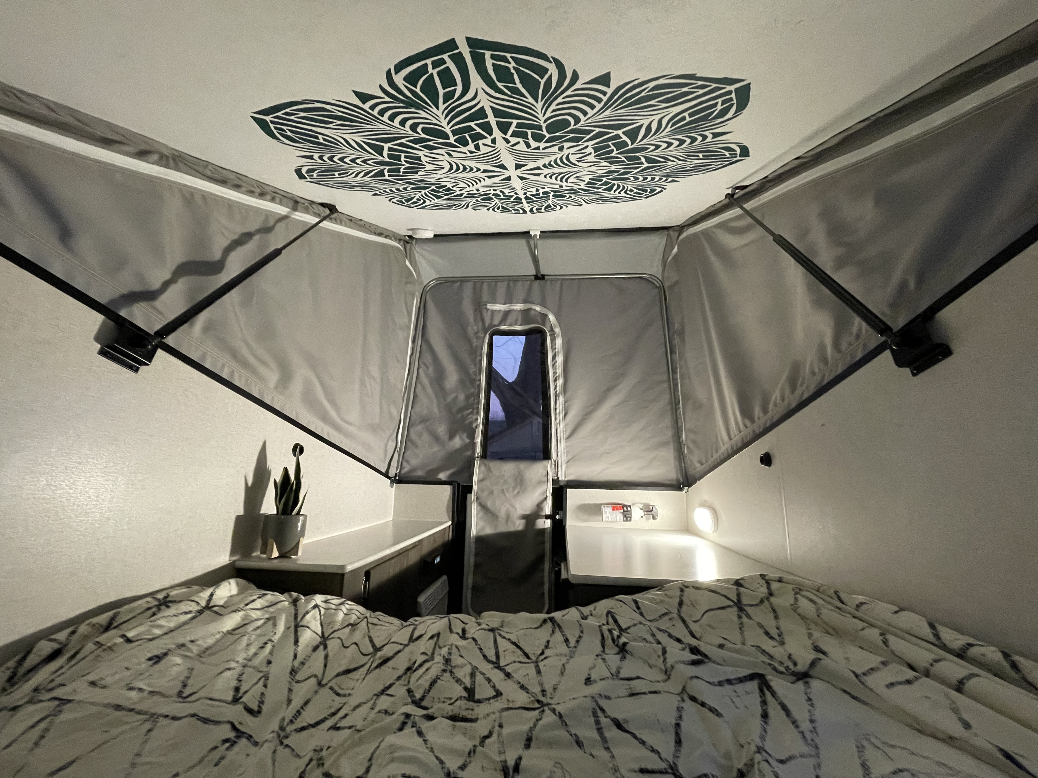 Inside a cozy RV rental: a patterned bed, mandala ceiling art, and gray pop-up fabric walls.. Coachmen Viking 2019