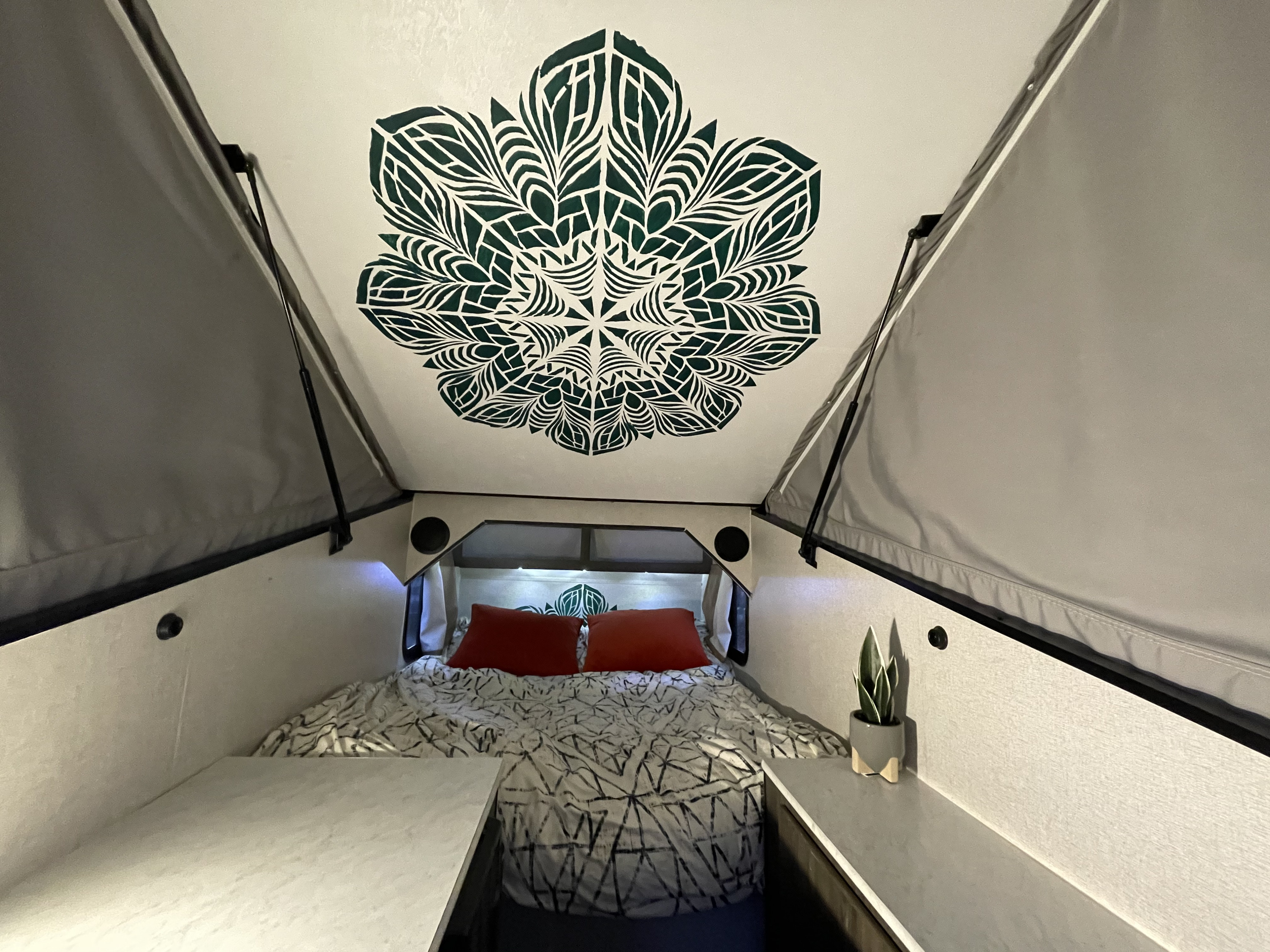 Cozy A-frame RV rental bedroom with a decorative mandala ceiling, comfy bed, and side storage.. Coachmen Viking 2019