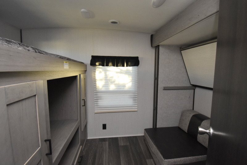 RV rental interior: bunk beds, built-in storage, window, and a dark gray sofa opposite a wall-mounted screen.. Other M-3385 2020
