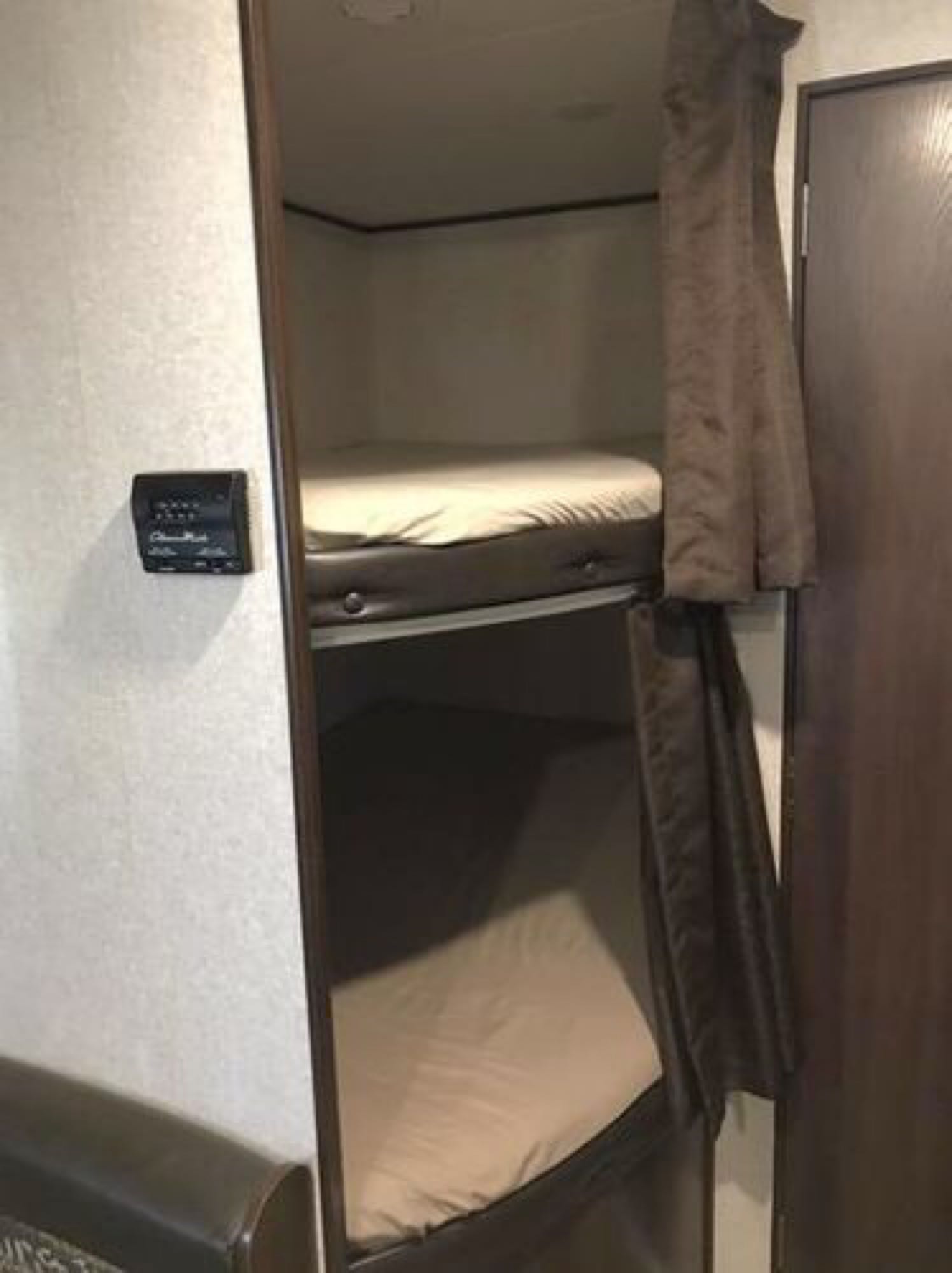 RV rental interior features stacked bunk beds with curtains and a wall thermostat, ideal for comfortable camping trips.. Jayco Jay Flight 2018