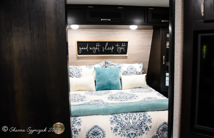 Step into a cozy RV rental bedroom. Features blue & white bedding, a turquoise throw, and "good night sleep tight" decor.. Jayco Jay Flight 2021