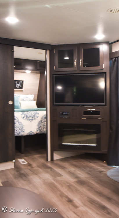 RV rental: Modern entertainment center with TV, fireplace, and an adjacent cozy bedroom with blue and white bedding.. Jayco Jay Flight 2021