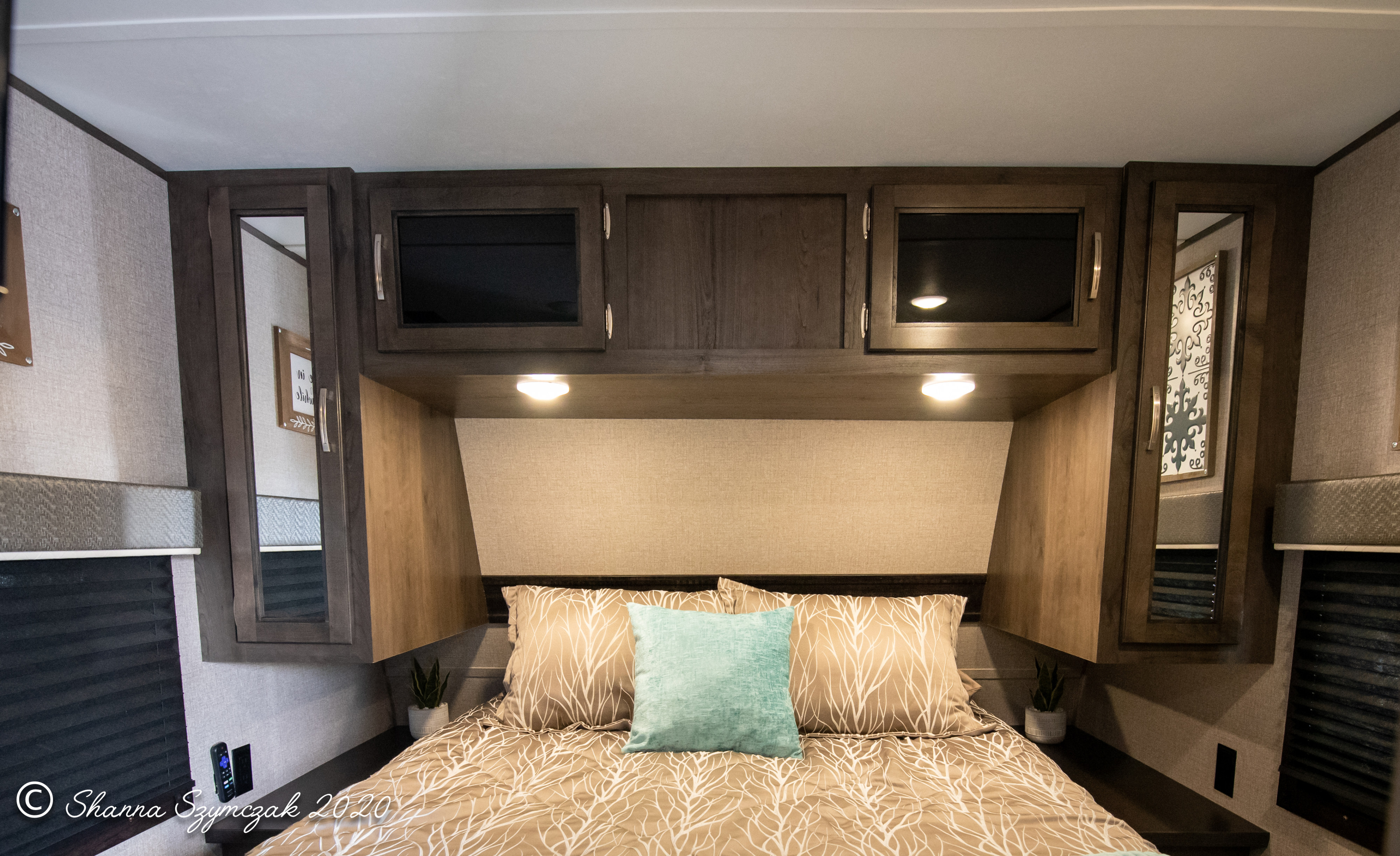 Comfortable RV rental bedroom with patterned bed, teal pillow, and dark wood cabinets, perfect for a cozy interior.. Jayco Jay Flight 2020