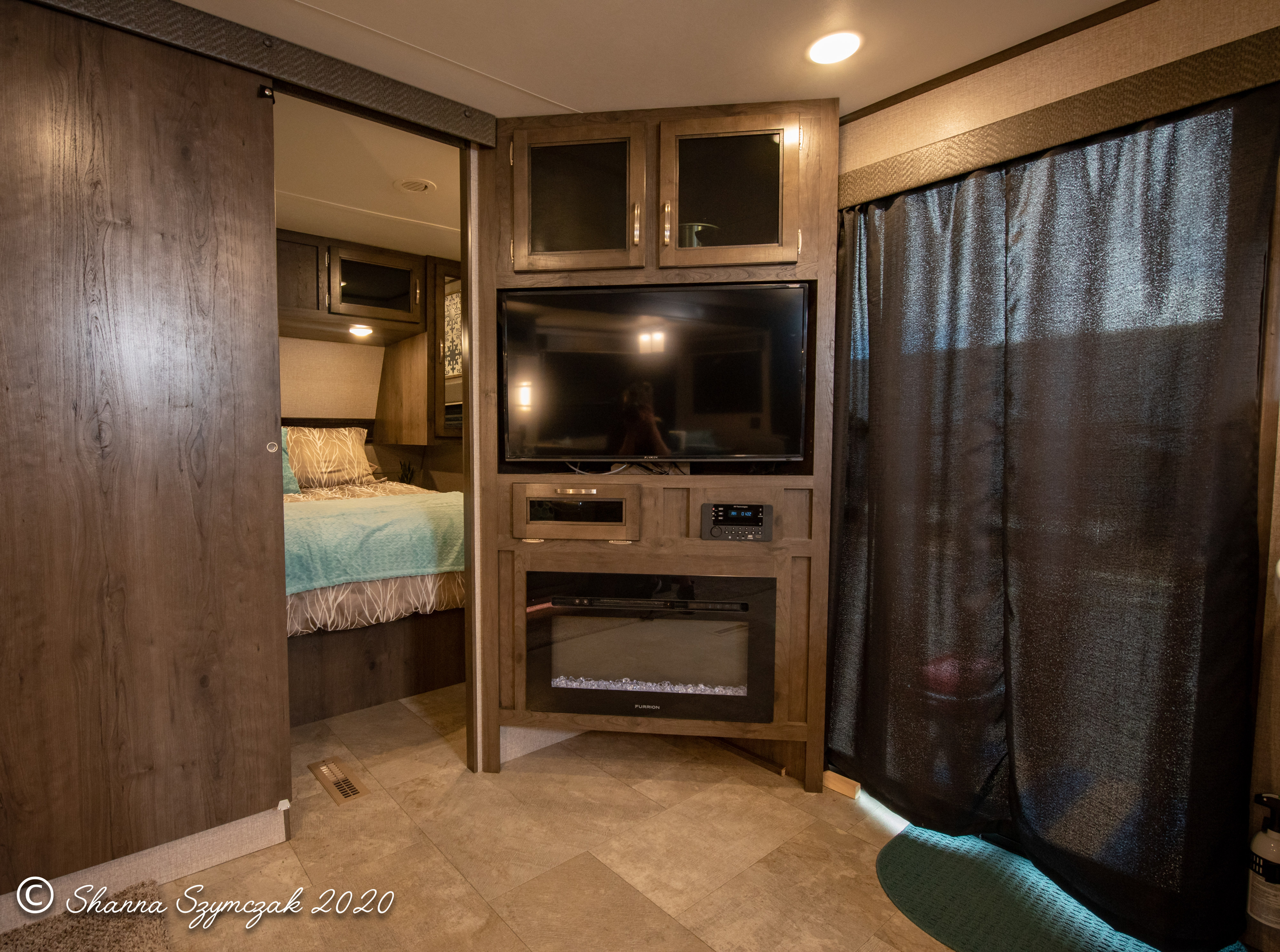Inside a modern rv rental: living area with built-in TV, fireplace, and sliding door to bedroom. Cozy and functional.. Jayco Jay Flight 2020