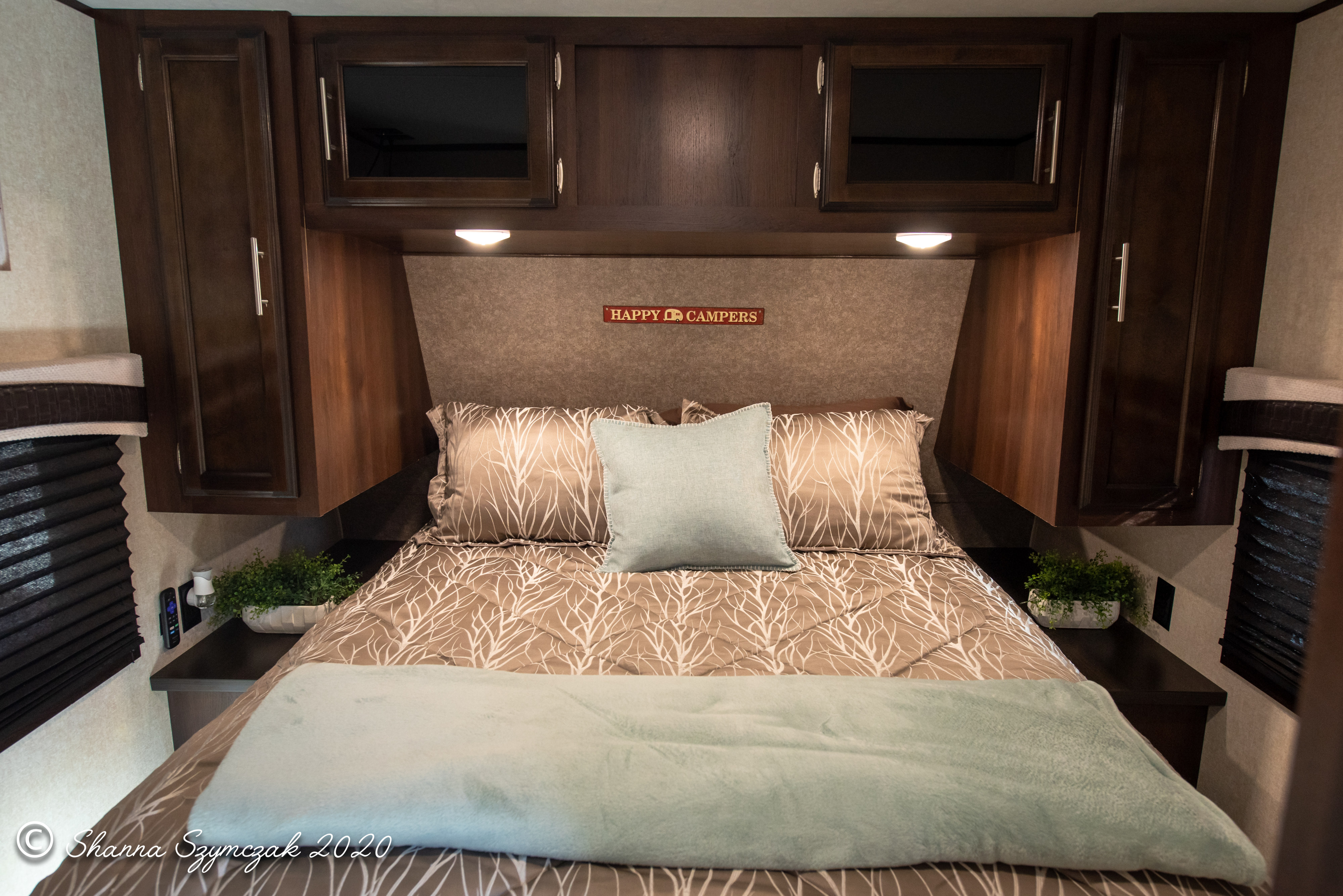 Cozy RV rental bedroom featuring a brown bed with tree-patterned bedding, a light blue blanket, and overhead storage.. Jayco Jay Flight 2020