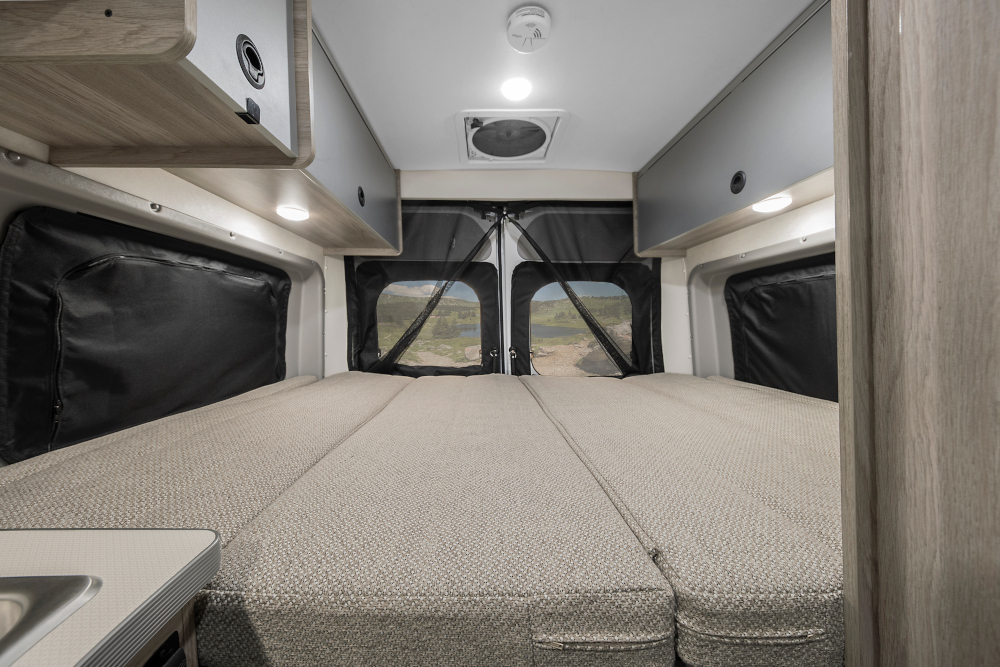 RV rental camper van interior: large bed, overhead storage, and scenic views through rear screened windows. Perfect for adventures.. Winnebago SOLIS 59 PX Winnebago Camper 2021