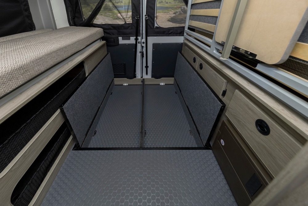 RV rental camper interior: versatile bed, open storage bins, and hinged floor panels for extensive cargo capacity.. Winnebago SOLIS 59 PX Winnebago Camper 2021