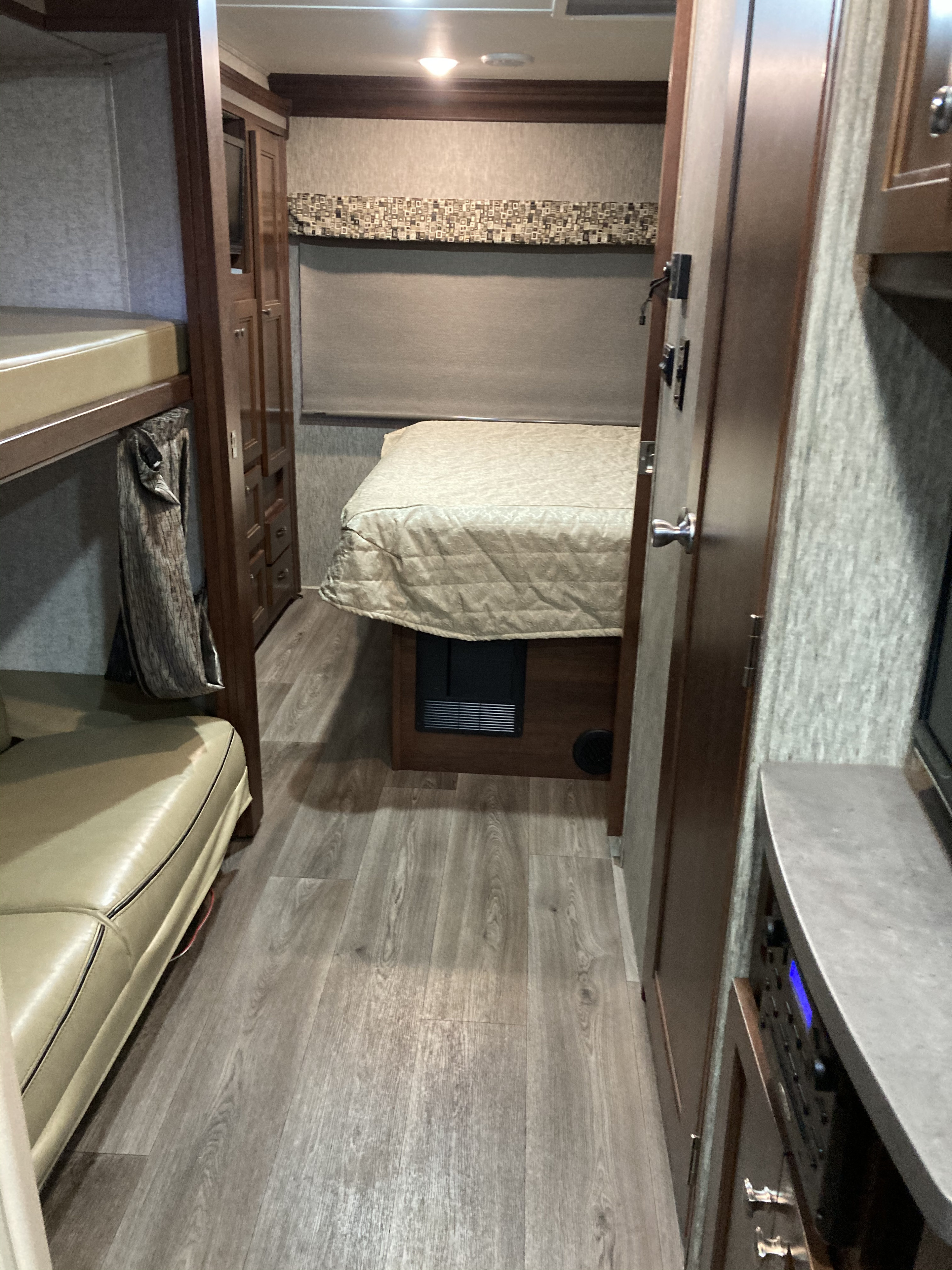RV rental interior showcasing bunk beds, a master bed, wood floors, and an entertainment console. Functional and inviting.. Forest River Sunseeker 2017