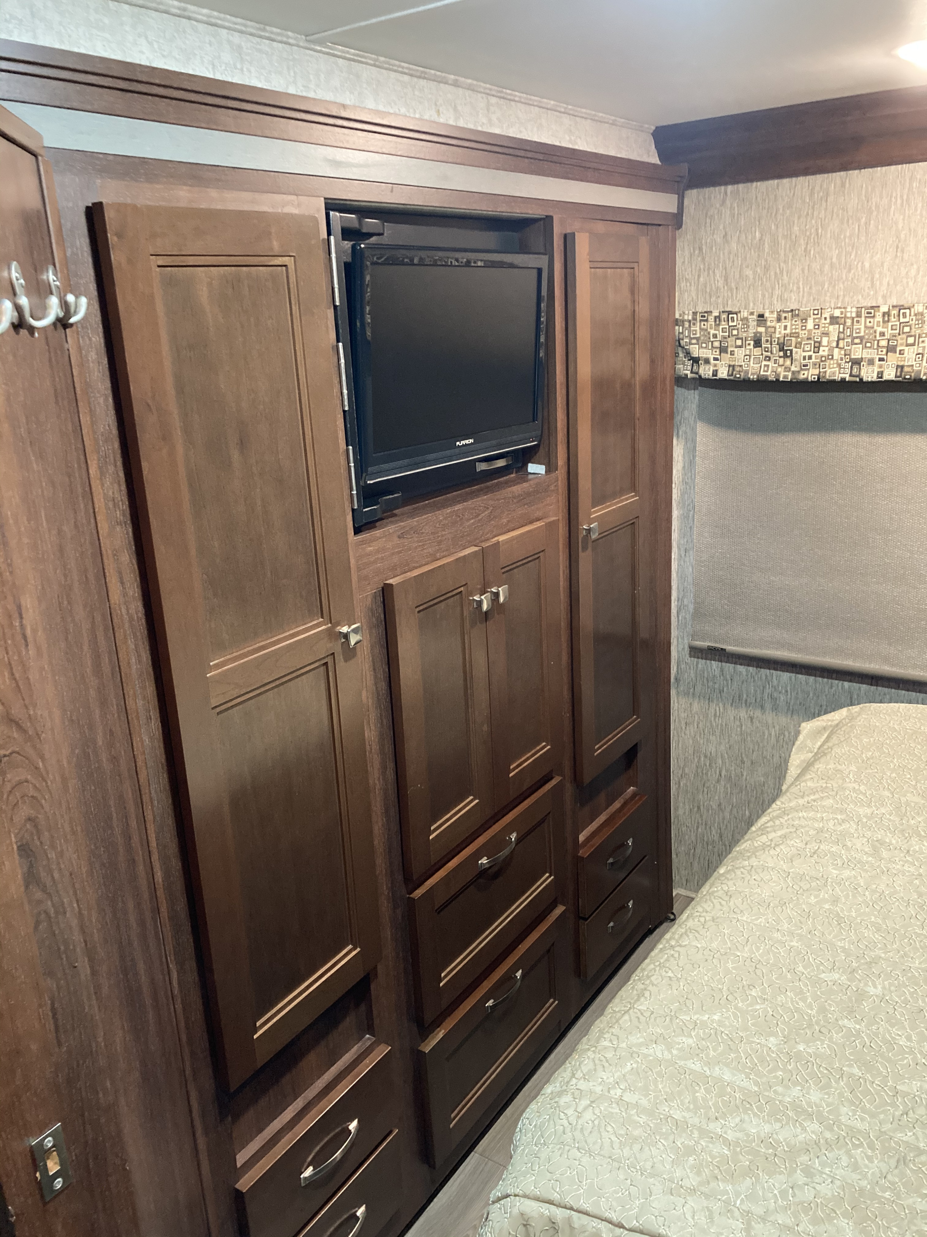 Experience comfort in your RV rental with this bedroom's dark wood cabinetry, built-in TV, and extensive storage.. Forest River Sunseeker 2017