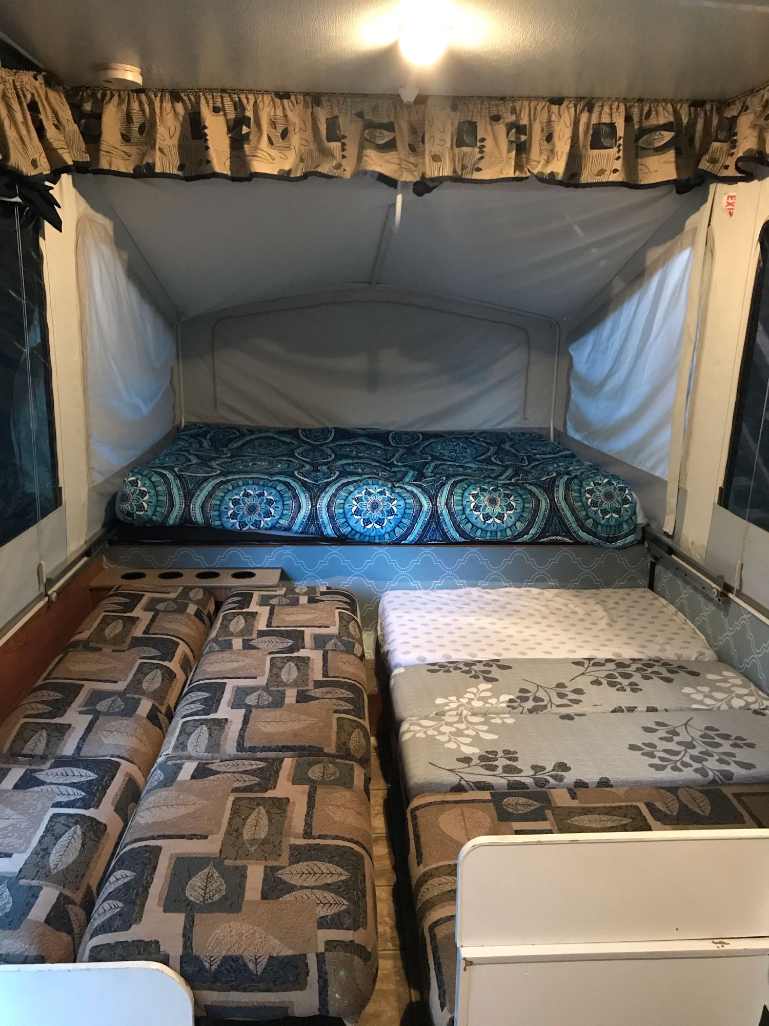 Inside a comfortable pop-up RV rental: features blue patterned main bed and cozy seating/bed areas. Ideal for camping trips.. Jayco JaySeries 2008