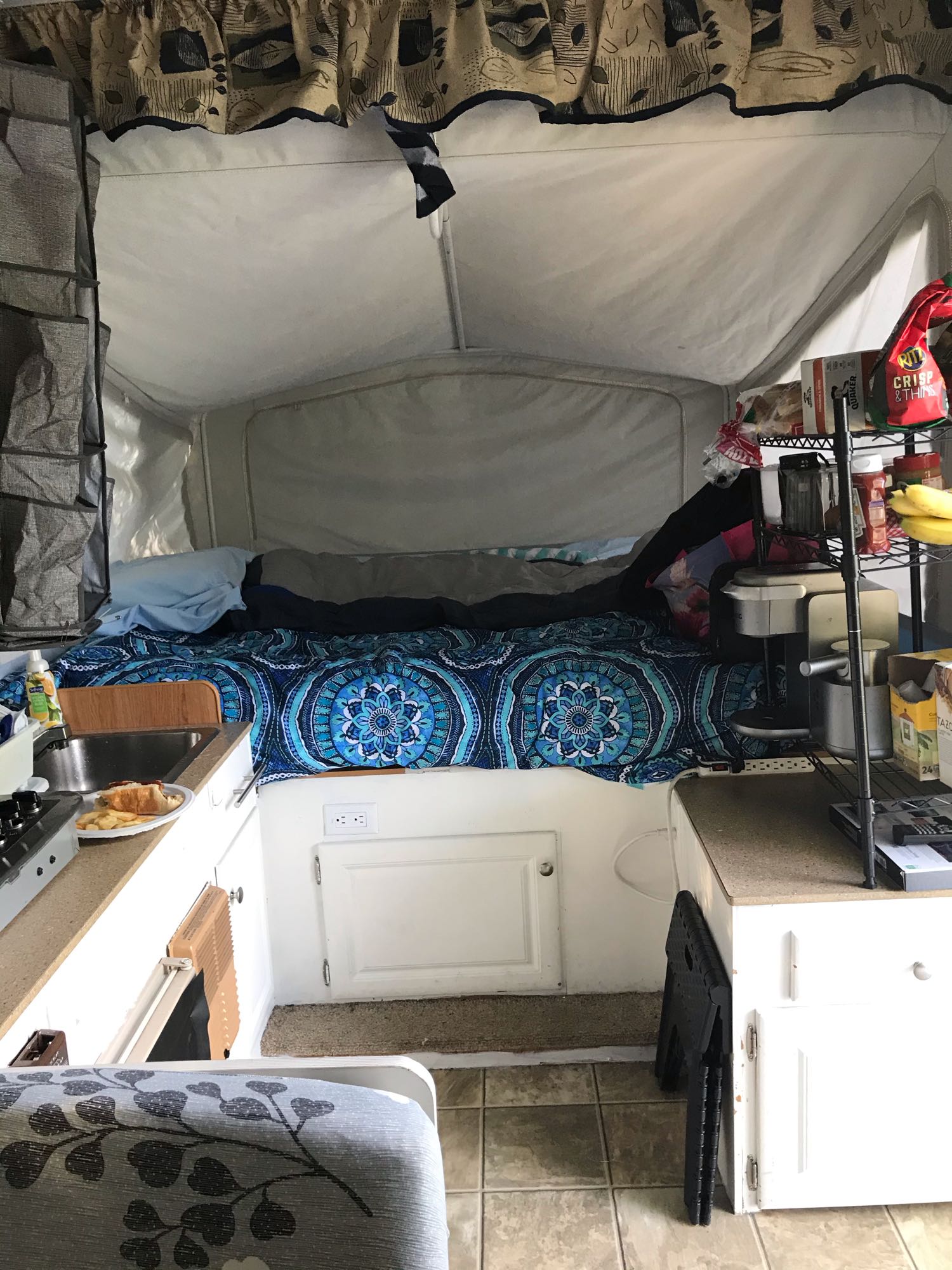 Pop-up RV rental interior: bed with blue blanket, compact kitchen, and organized supplies for a cozy stay.. Jayco JaySeries 2008