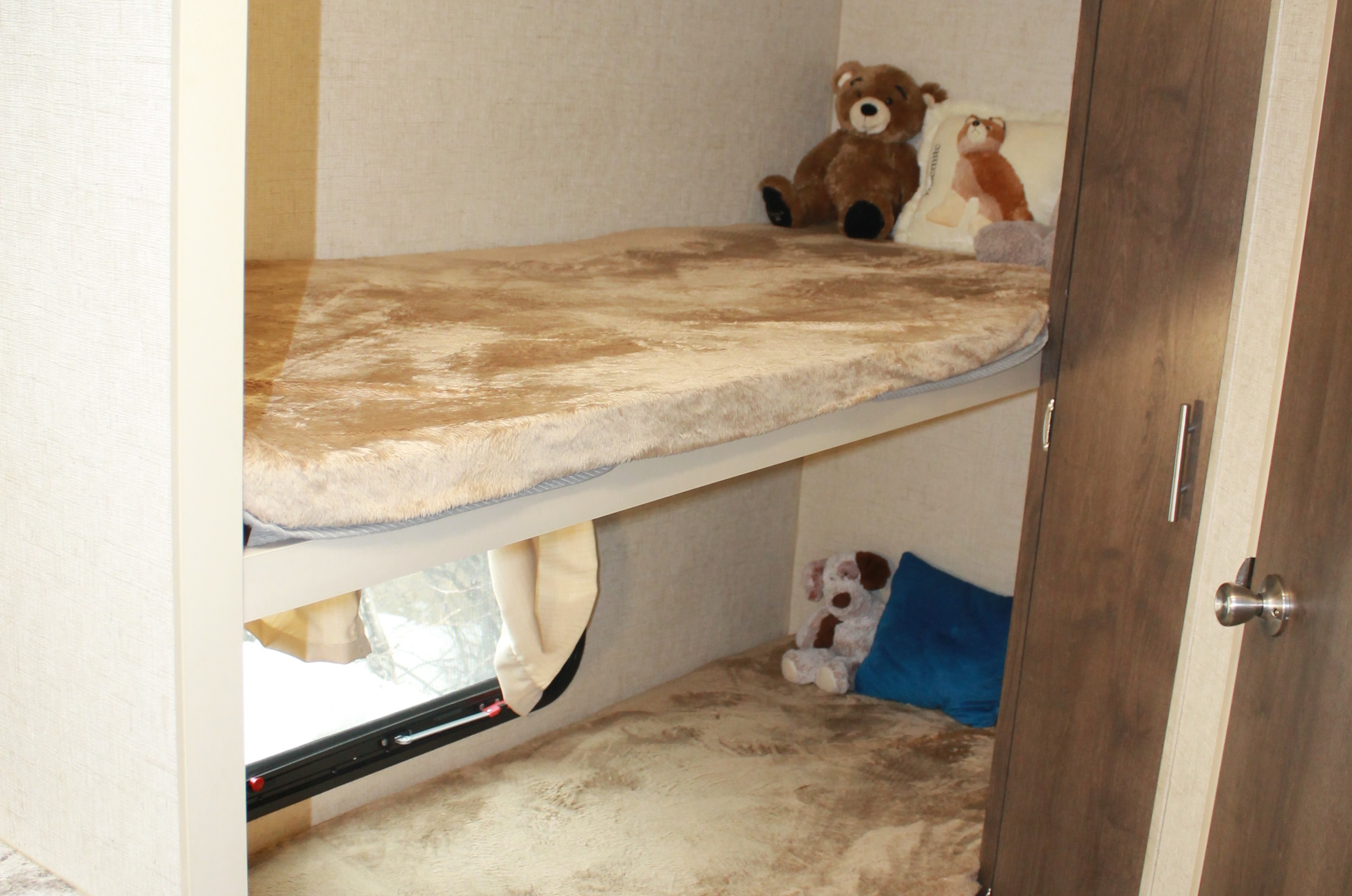 Compact RV rental bunk beds, fully made with plush bedding and toys for a cozy sleep.. K-Z Manufacturing Spree 2017