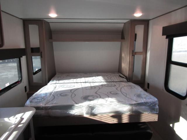 RV rental interior shows a compact sleeping area with a new mattress in plastic, overhead storage, and side windows.. Keystone Hideout 2021