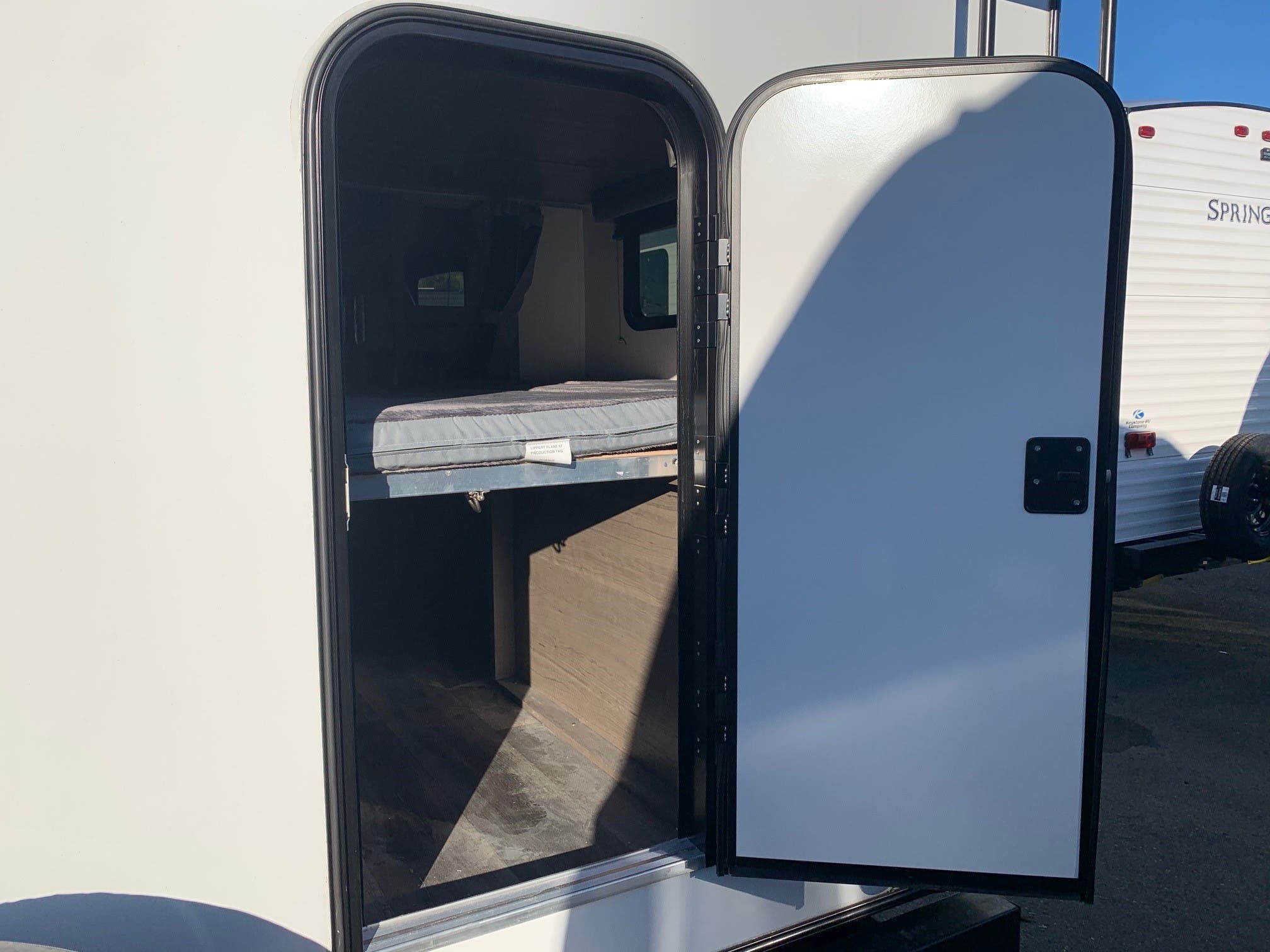 Open RV rental door reveals a cozy bunk bed with mattress and lower storage inside this white travel trailer.. Keystone Cougar Half-Ton 2021