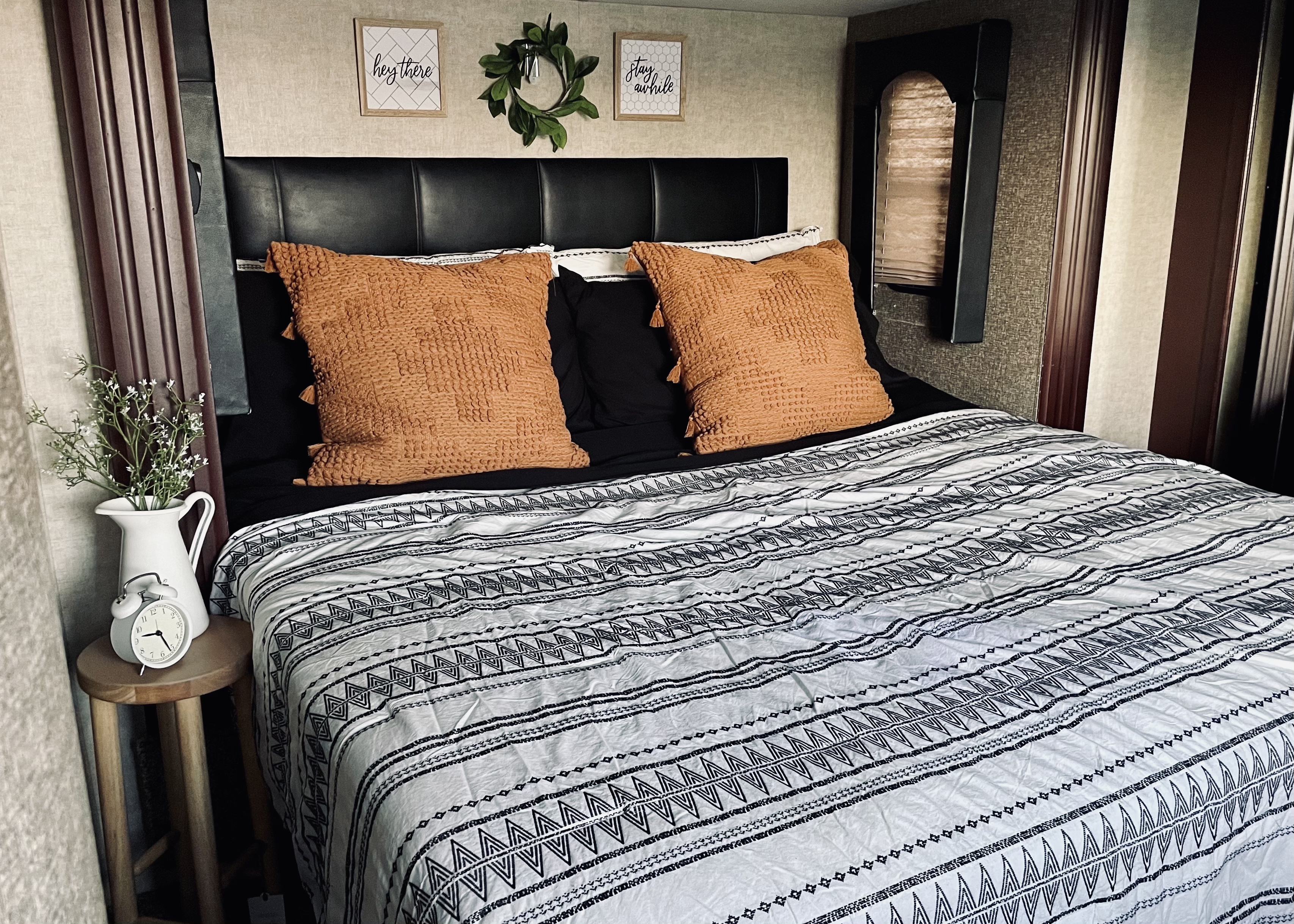 Stylish RV rental bedroom interior featuring black & white tribal bedding, orange pillows, and bedside decor.. Heartland RVs Road Warrior Toy Hauler 2015
