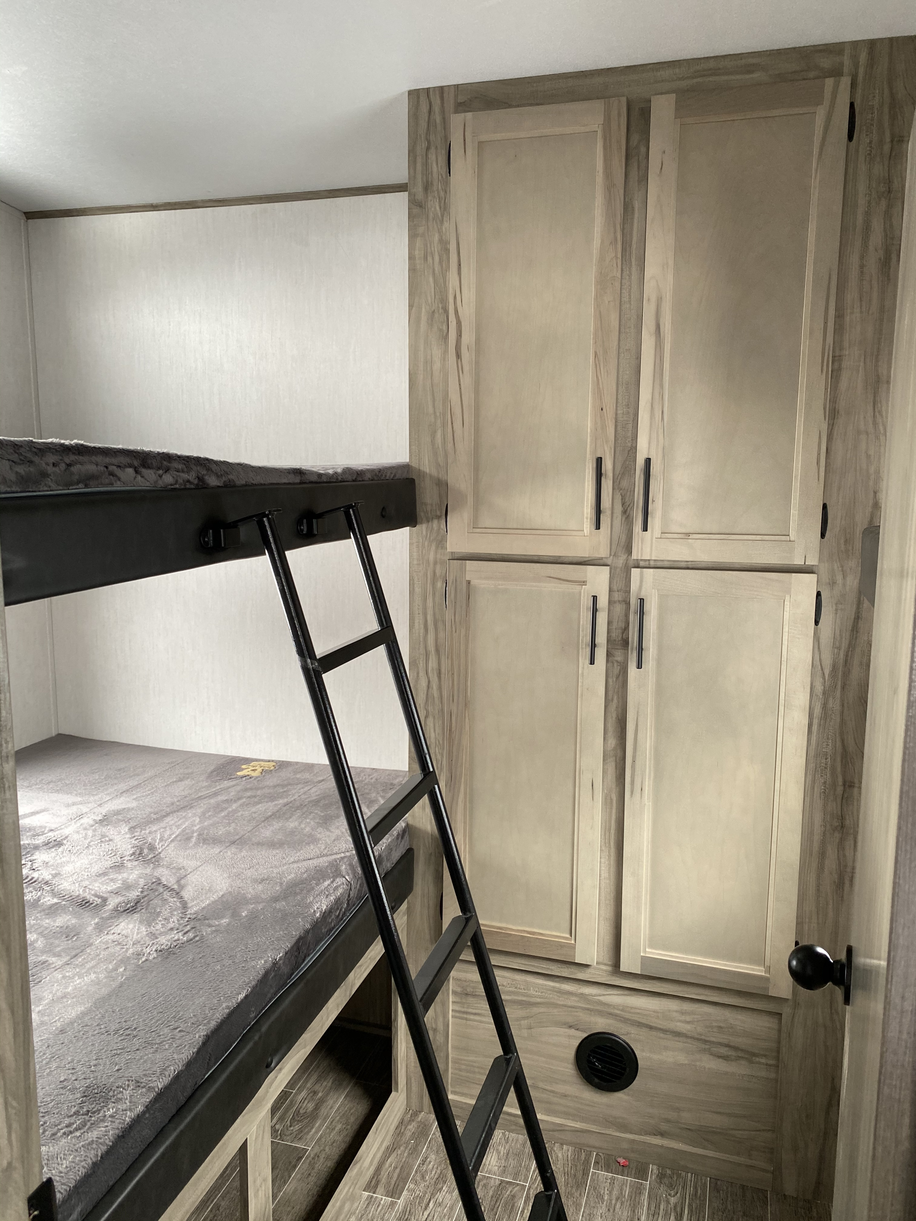 Cozy RV rental interior featuring bunk beds, a ladder, and light-wood cabinets for comfortable mobile living.. Forest River Artic Wolf 2021