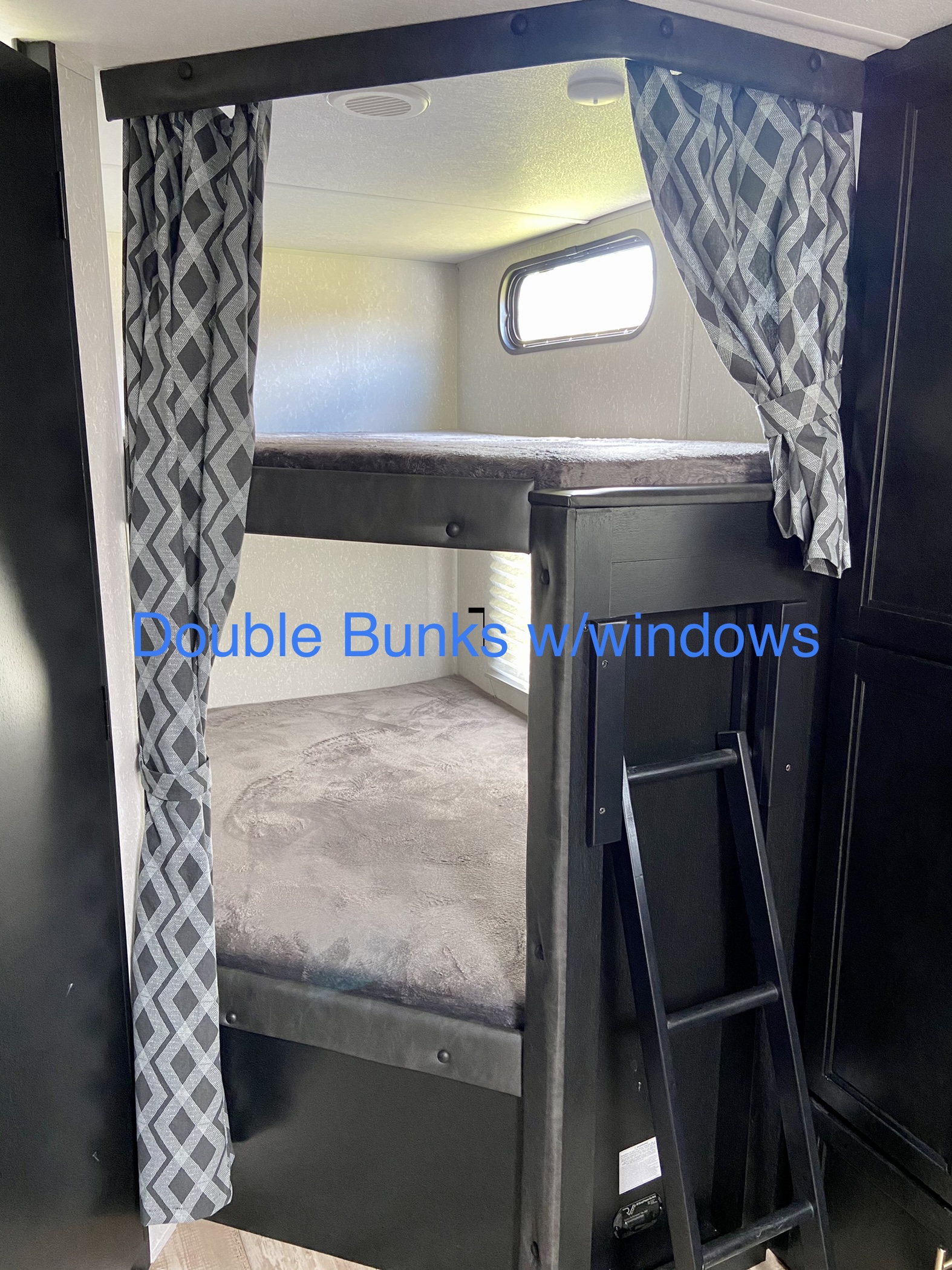 RV rental features double bunk beds with patterned curtains, windows, and a ladder for easy access. Ideal for guests.. Forest River Cherokee Grey Wolf 2021