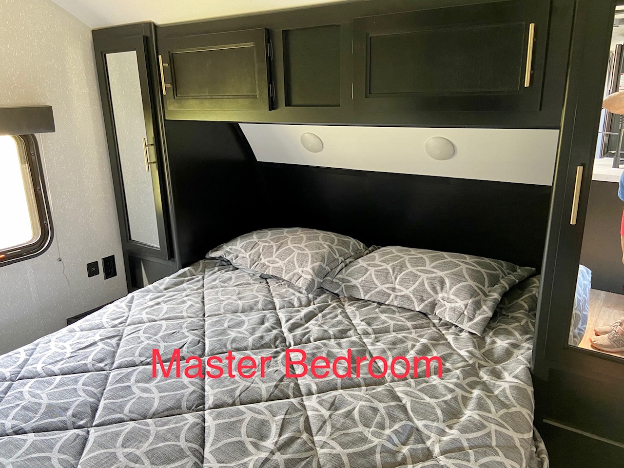 RV rental master bedroom with a comfortable bed, overhead storage, and mirrored wardrobes. Perfect for relaxing after your adventures.. Forest River Cherokee Grey Wolf 2021