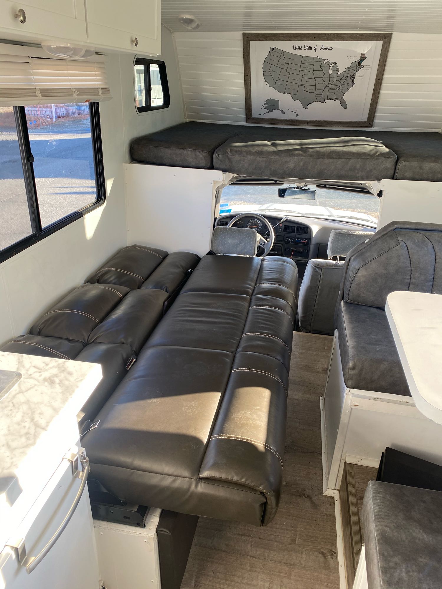 Spacious RV rental interior with convertible seating, cab-over bunk, US map, and modern finishes for comfortable travel.. Toyota Other 1991