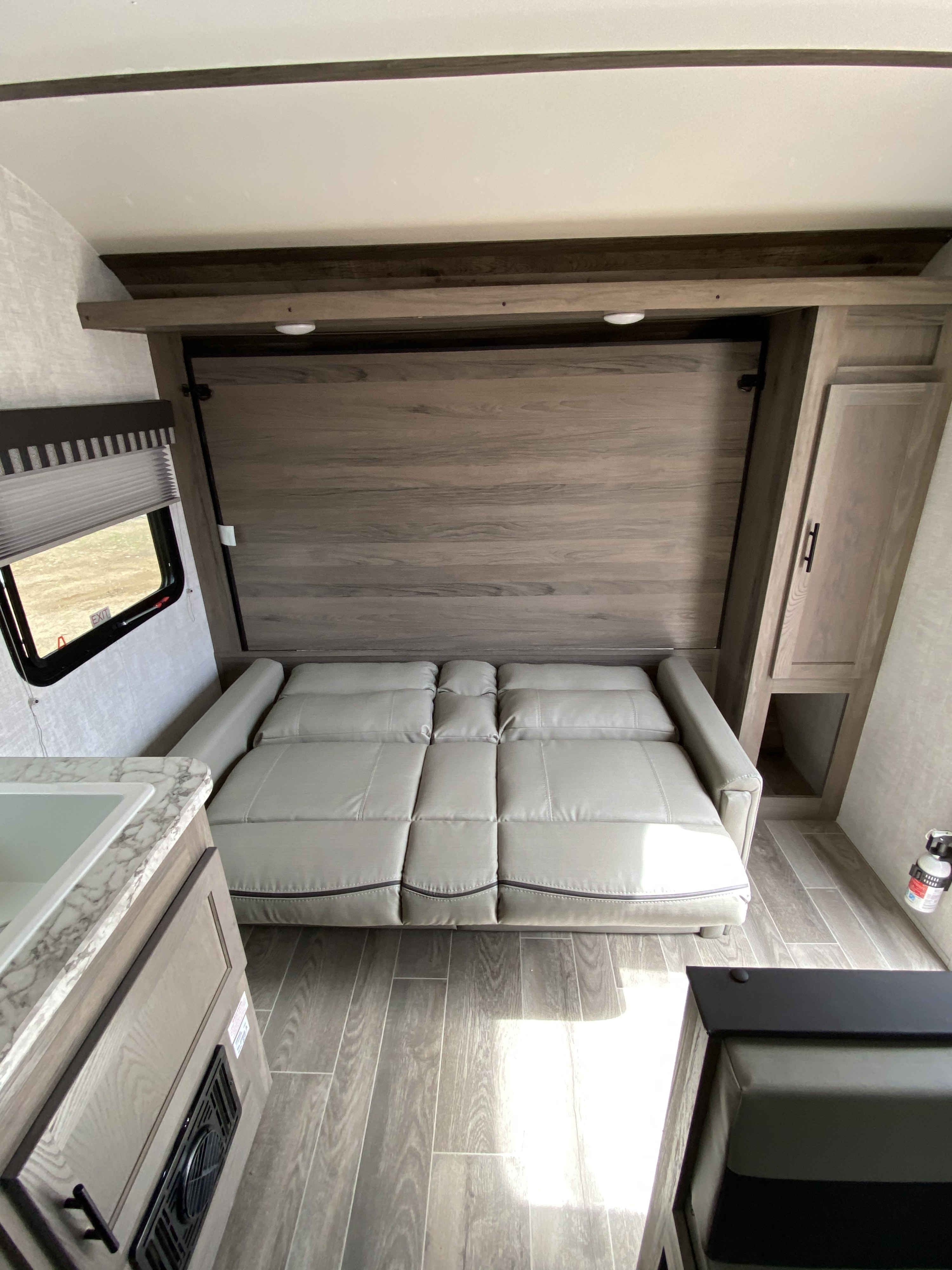 RV rental interior: light gray convertible sofa, wood-look flooring, compact kitchenette, and storage optimize this living space.. Gulf Stream Conquest Ultra 2021
