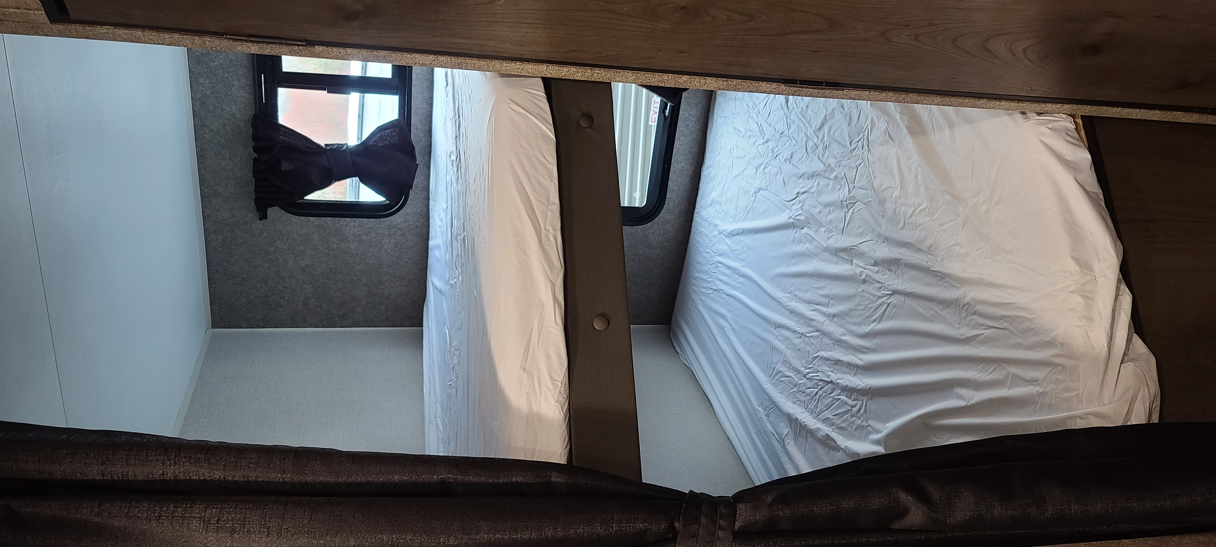 RV rental bunk beds: Two sleeping areas with white sheets and windows with dark shades, offering compact space.. Open Range 26BHS 2021