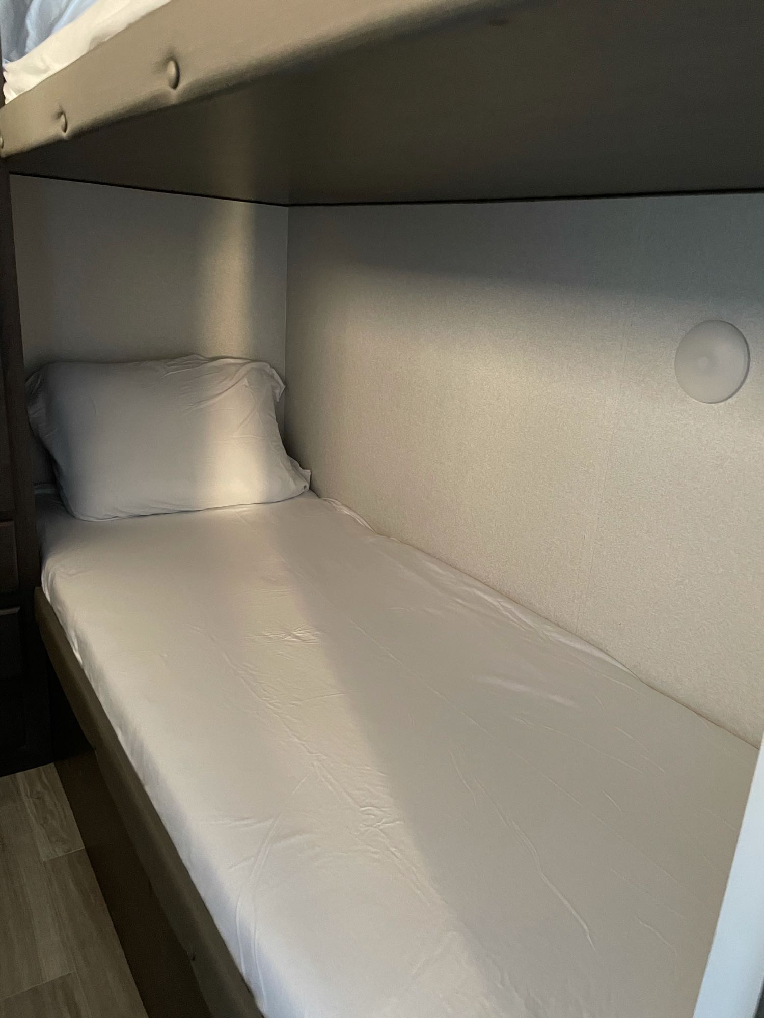 Cozy RV rental bunk bed with white sheets and pillow, ready for sleep in a compact, organized space.. Forest River Cruise Lite 2020