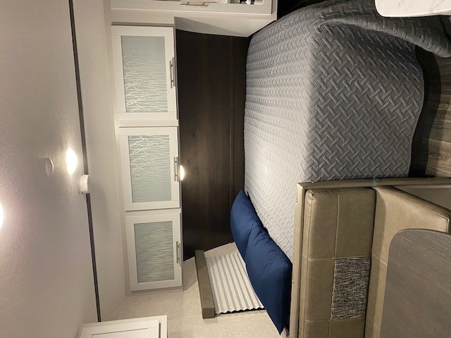 RV rental: Cozy interior features a gray quilted bed, blue pillows, tan dinette seating, and white overhead cabinets.. Keystone Bullet 2021