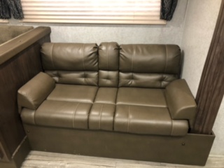 This inviting brown RV rental sofa offers comfortable seating for two. Its cushioned design ensures a relaxing journey.. Forest River Grey Wolf 29BH 2018