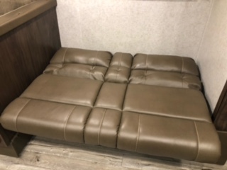 Inside an rv rental: a flat, brown pull-out sofa cushion converted into a bed. Ideal for compact sleeping in a travel trailer.. Forest River Grey Wolf 29BH 2018