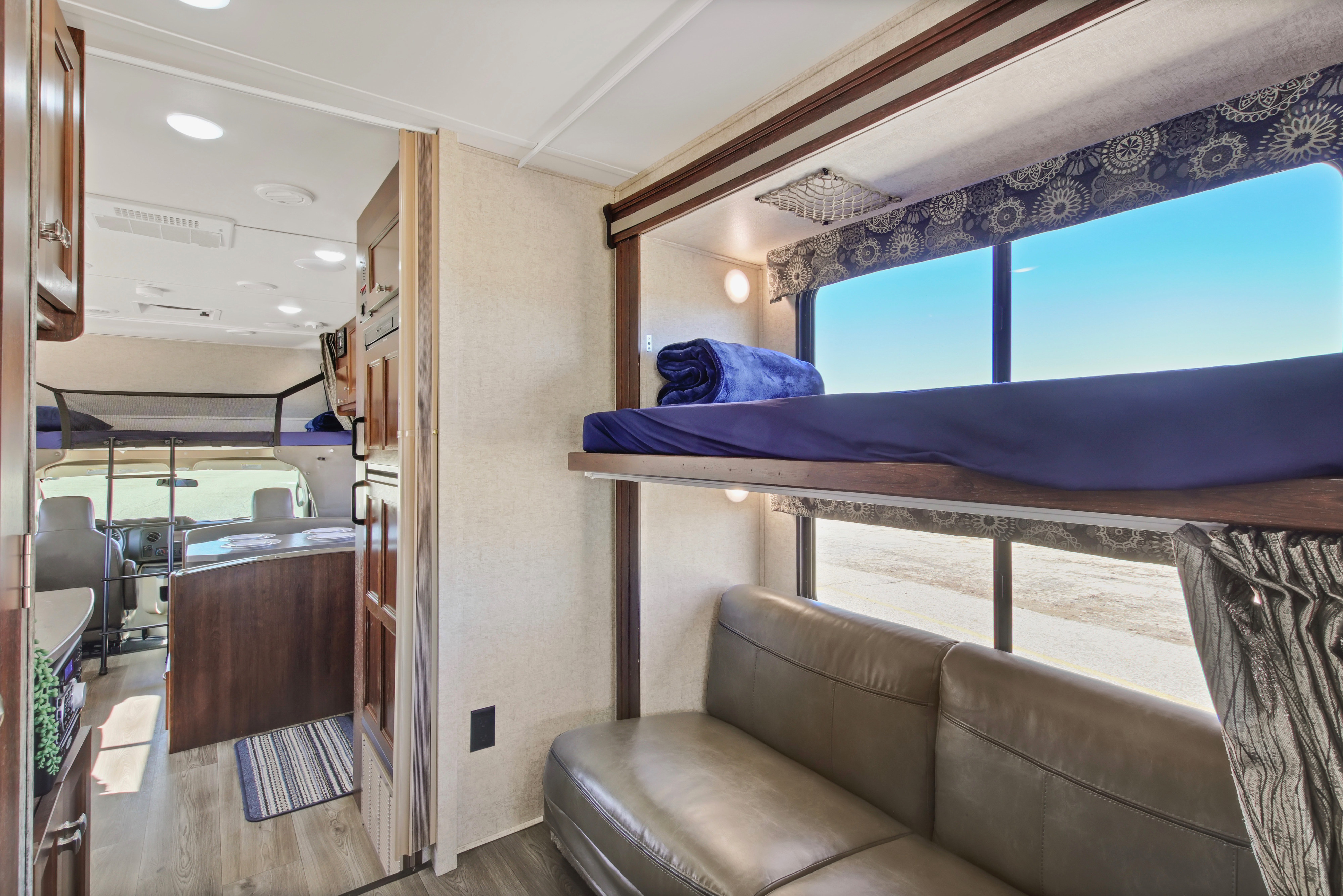 Spacious RV rental interior featuring a bunk bed setup, cozy sofa, and view into the cockpit, ready for adventure.. Forest River Sunseeker 2018