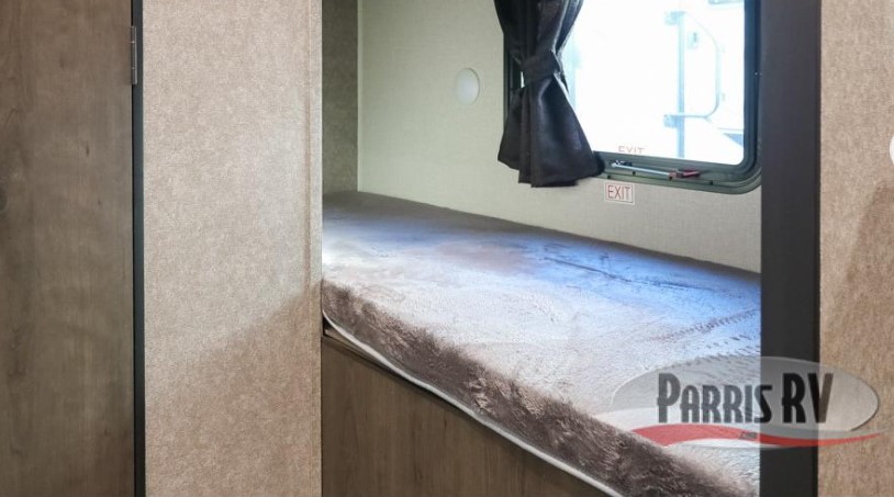 This RV rental's cozy bunk bed features a plush grey mattress, window with curtains, small light, and visible EXIT sign.. Highland Ridge RV Open Range 2021