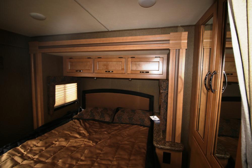 Cozy RV rental bedroom featuring a full bed, overhead storage cabinets, and a mirrored wardrobe, perfect for comfortable travel.. Thor Motor Coach Freedom Elite 22FE 2017
