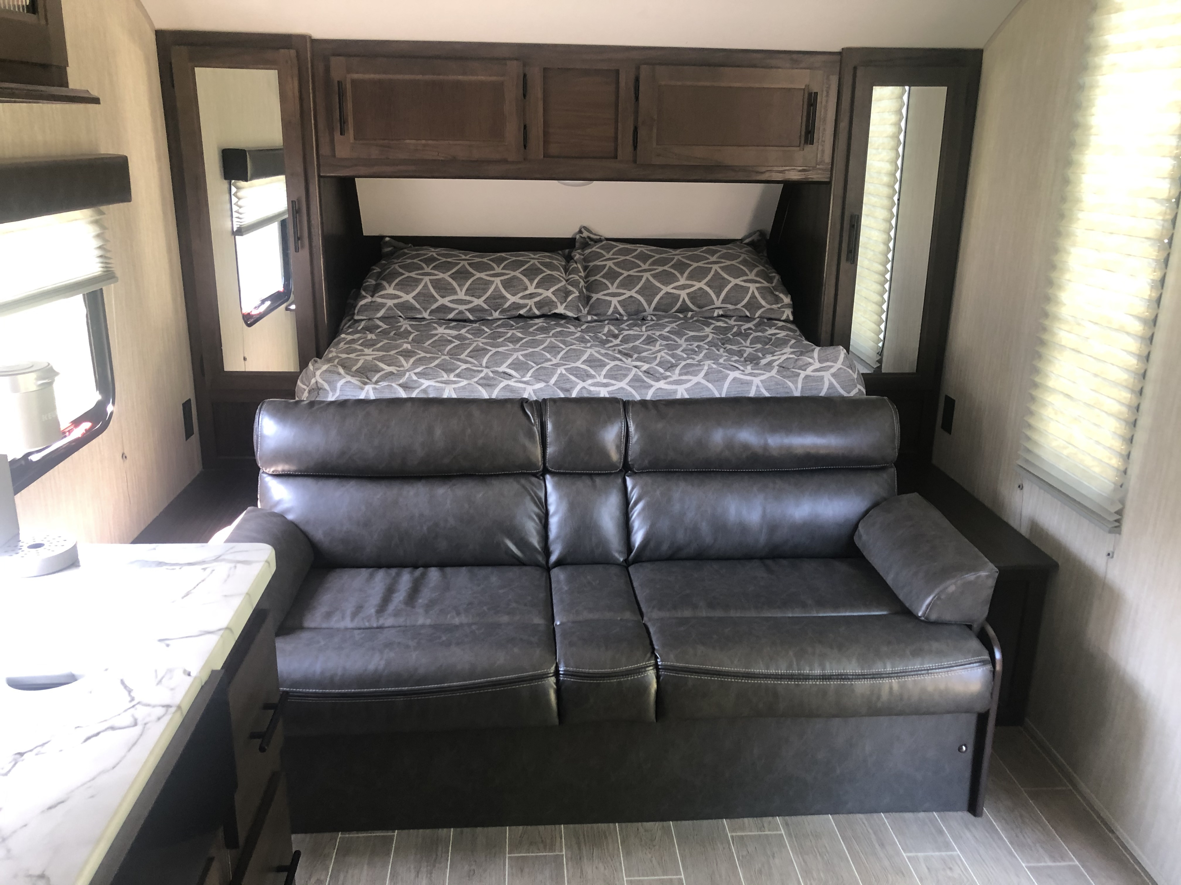 Comfortable RV rental interior with a cozy queen bed, overhead storage, and inviting sofa, ideal for your next adventure.. Forest River Cherokee Grey Wolf 22MKSE 2020