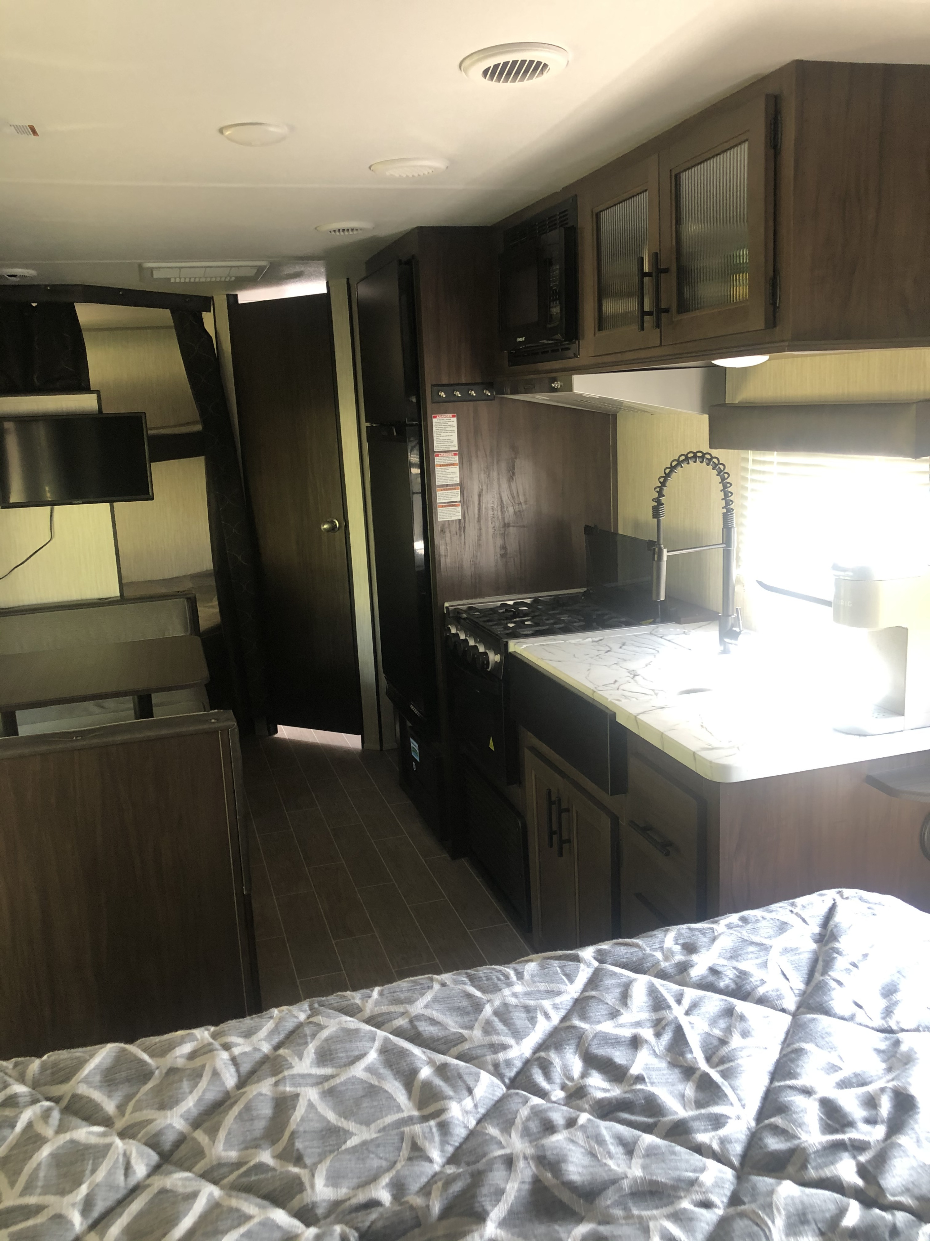 Bright RV rental interior: kitchen with modern appliances, bunk beds, and cozy main sleeping area shown.. Forest River Cherokee Grey Wolf 22MKSE 2020