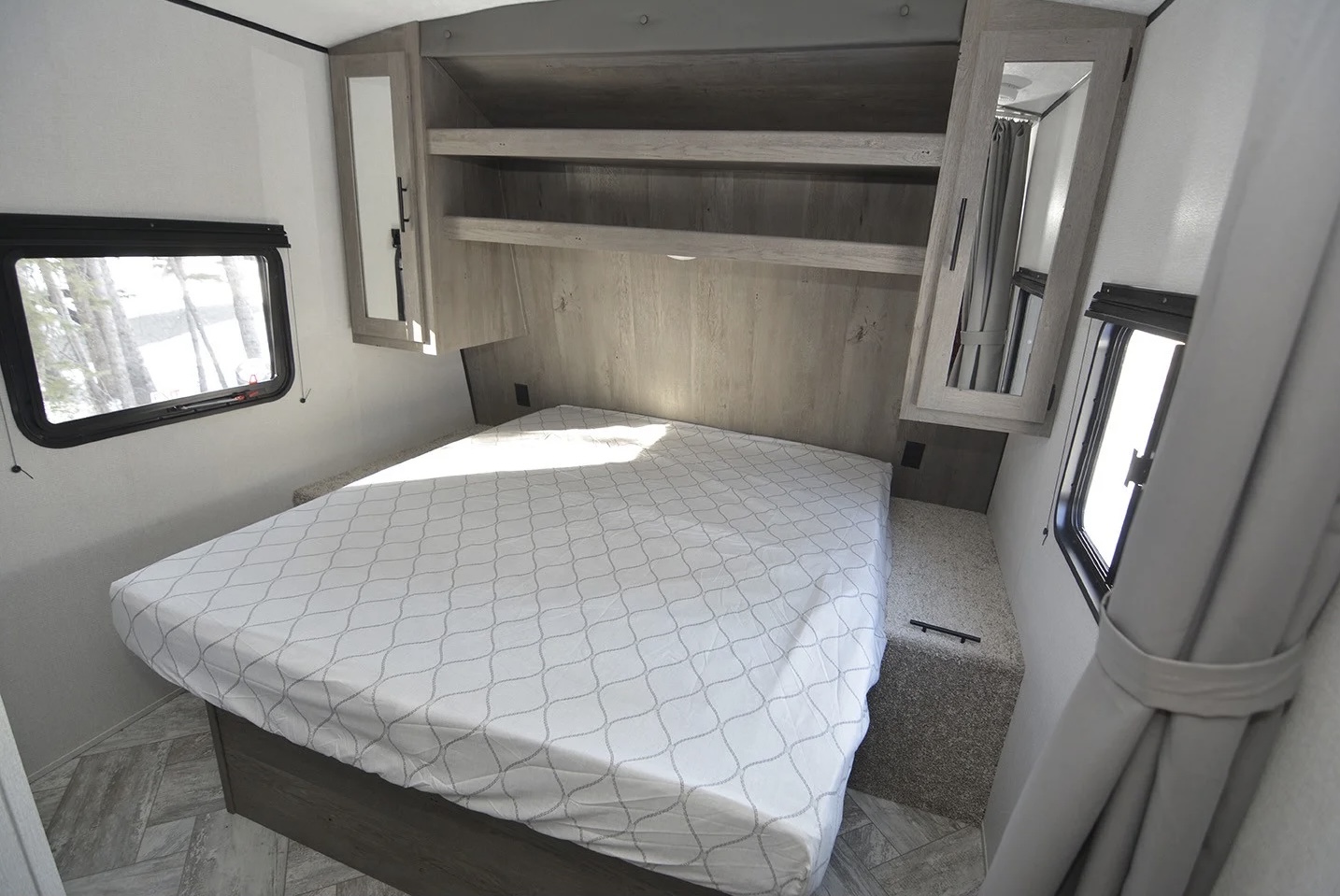 Comfortable RV rental bedroom featuring a queen bed, built-in shelving, and scenic windows.. Keystone springdale 202QBWE 2021