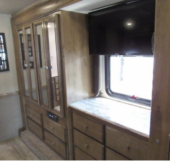 RV rental interior: wood wardrobe with mirrored doors, ample drawers, and TV over window. Efficient, cozy living space.. Fleetwood Flair 2020