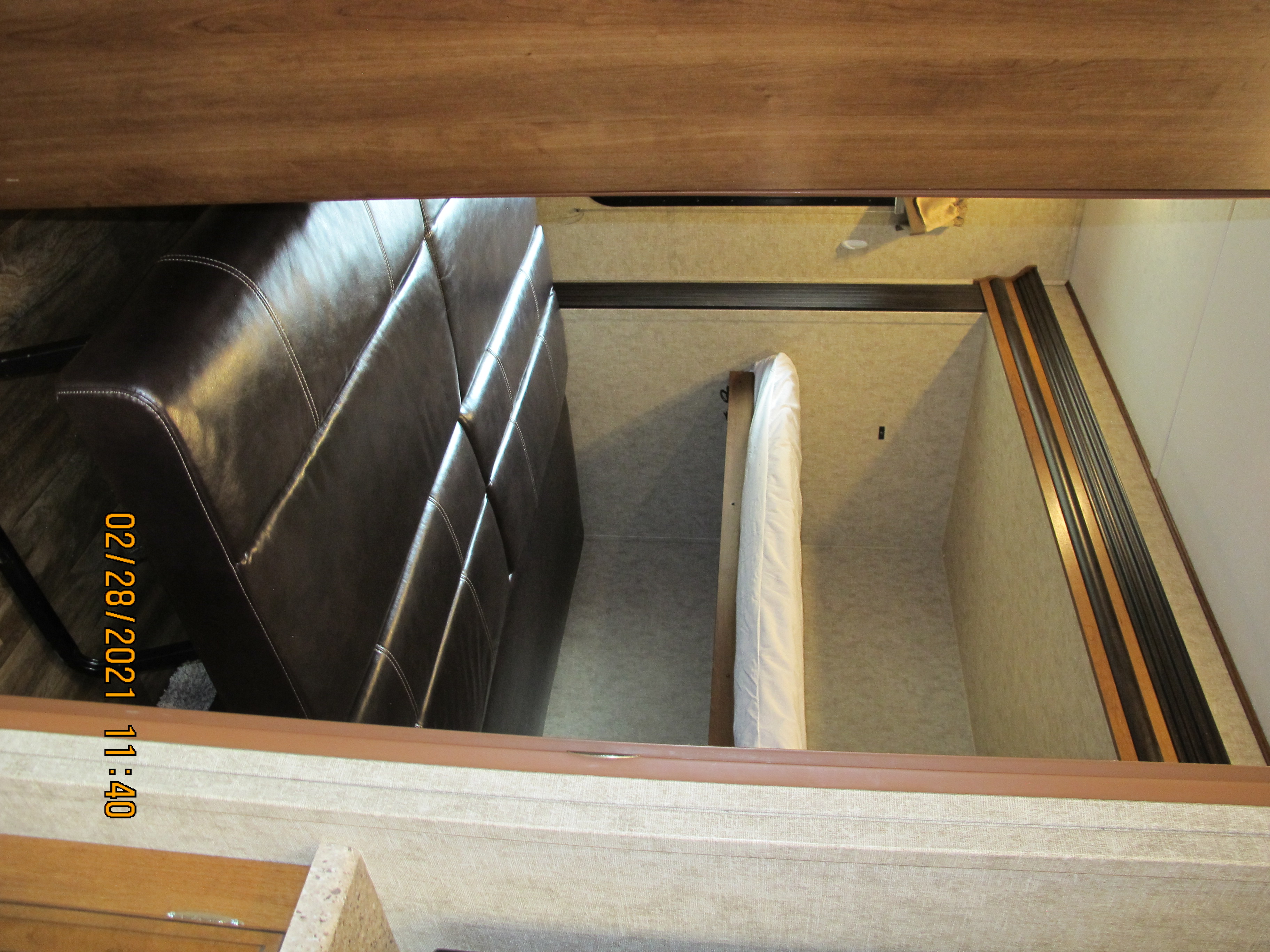 Overhead view of an rv rental's interior, showing a dark brown leather sofa and a narrow bed with white linens. (Feb 28, 2021). Other Lacrosse 2017