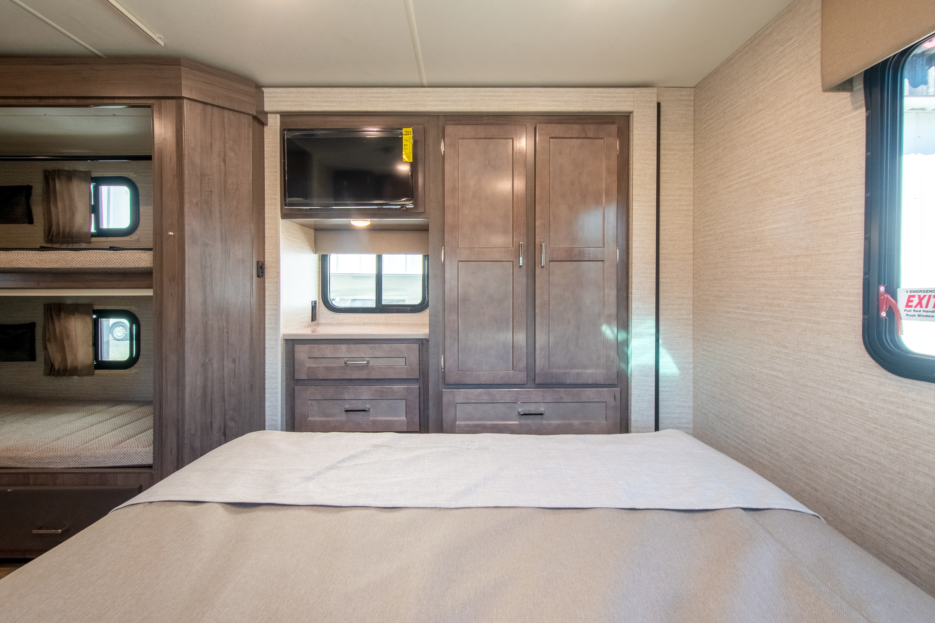 Comfortable RV rental interior featuring a main bed, bunk beds, built-in storage, and TV for a cozy travel experience.. Winnebago Minnie Winnie 2024